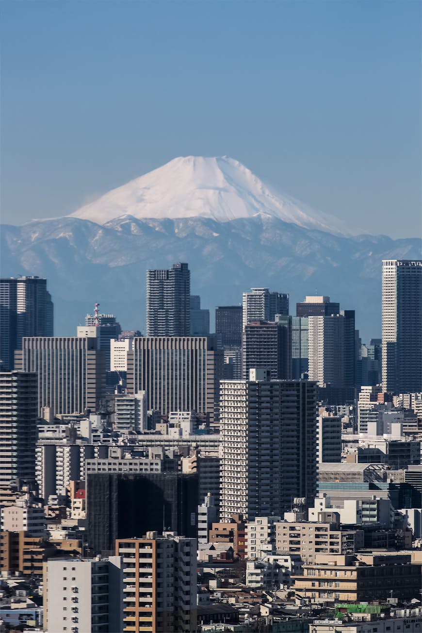 Det snötäckta berget Fuji skymtar över Tokyos skyline