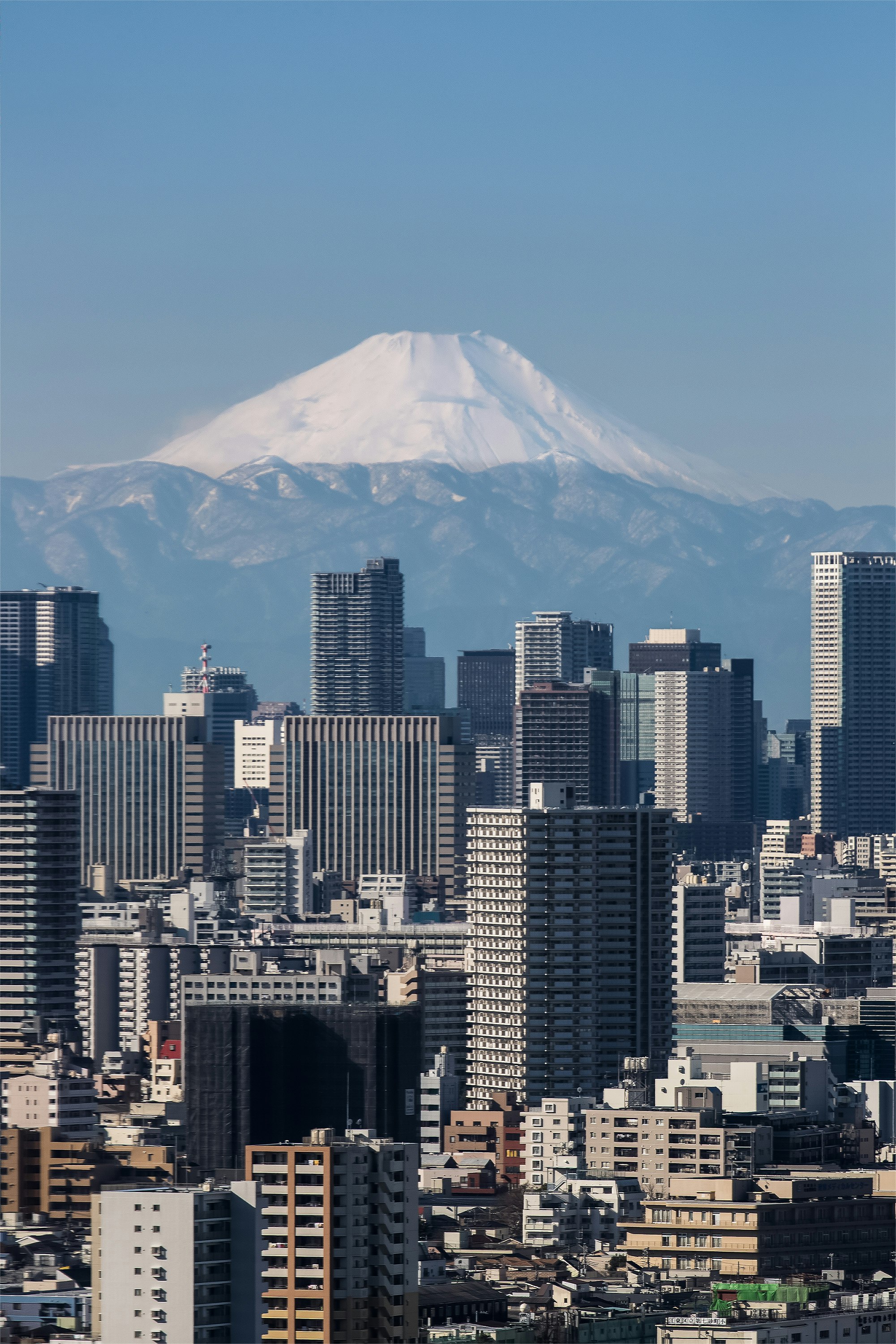 The snow-covered Mt Fuji looms over the Tokyo skyline