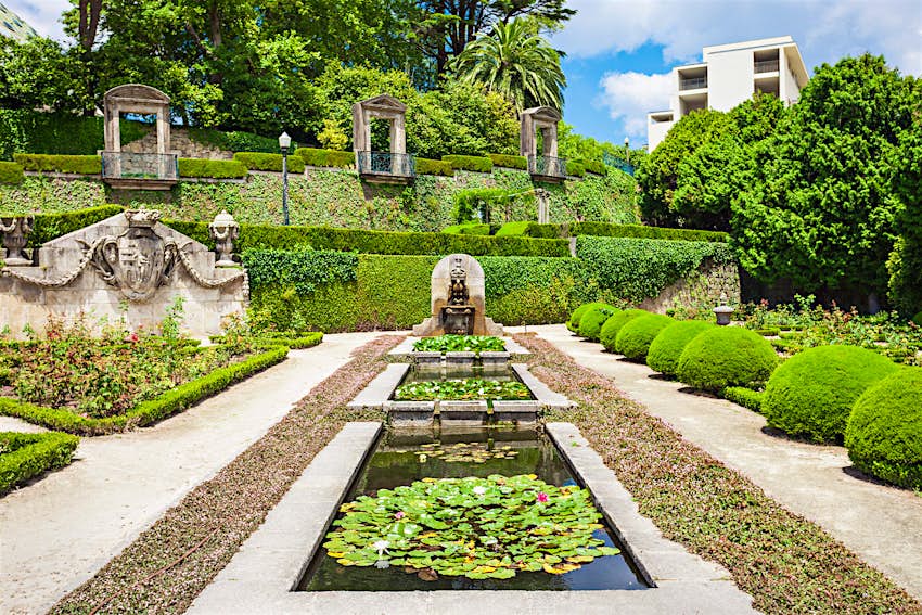 Three ponds filled with lily pads sit end to end, with a fountain at the end; heavily manicured hedges and shrubs fill the remainder of the garden, with ivy climbing up the walls at the end where there are three Juliet balconies.