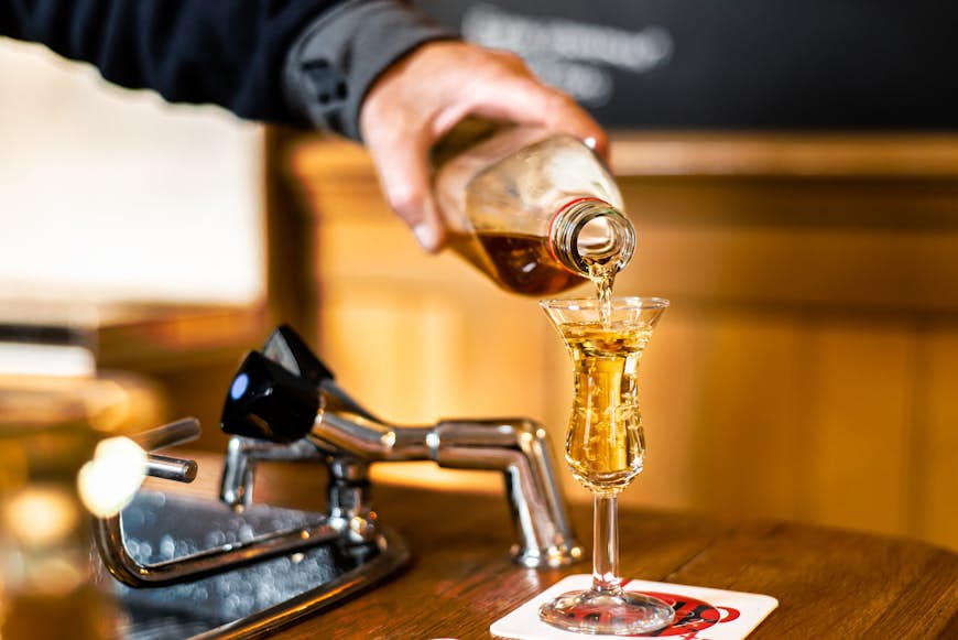 En bartender i Amsterdam häller upp jenever/genever i ett tulpanshotglas, som en del av en tradition som kallas kopstootje.