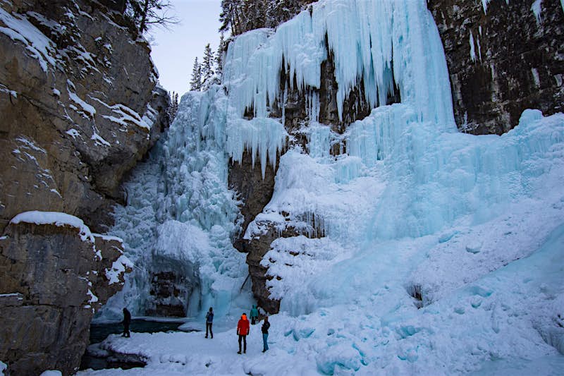 People stand at the bottom of a frozen waterfall in Johnston Canyon in Canada during winter at Banff and Lake Louise
