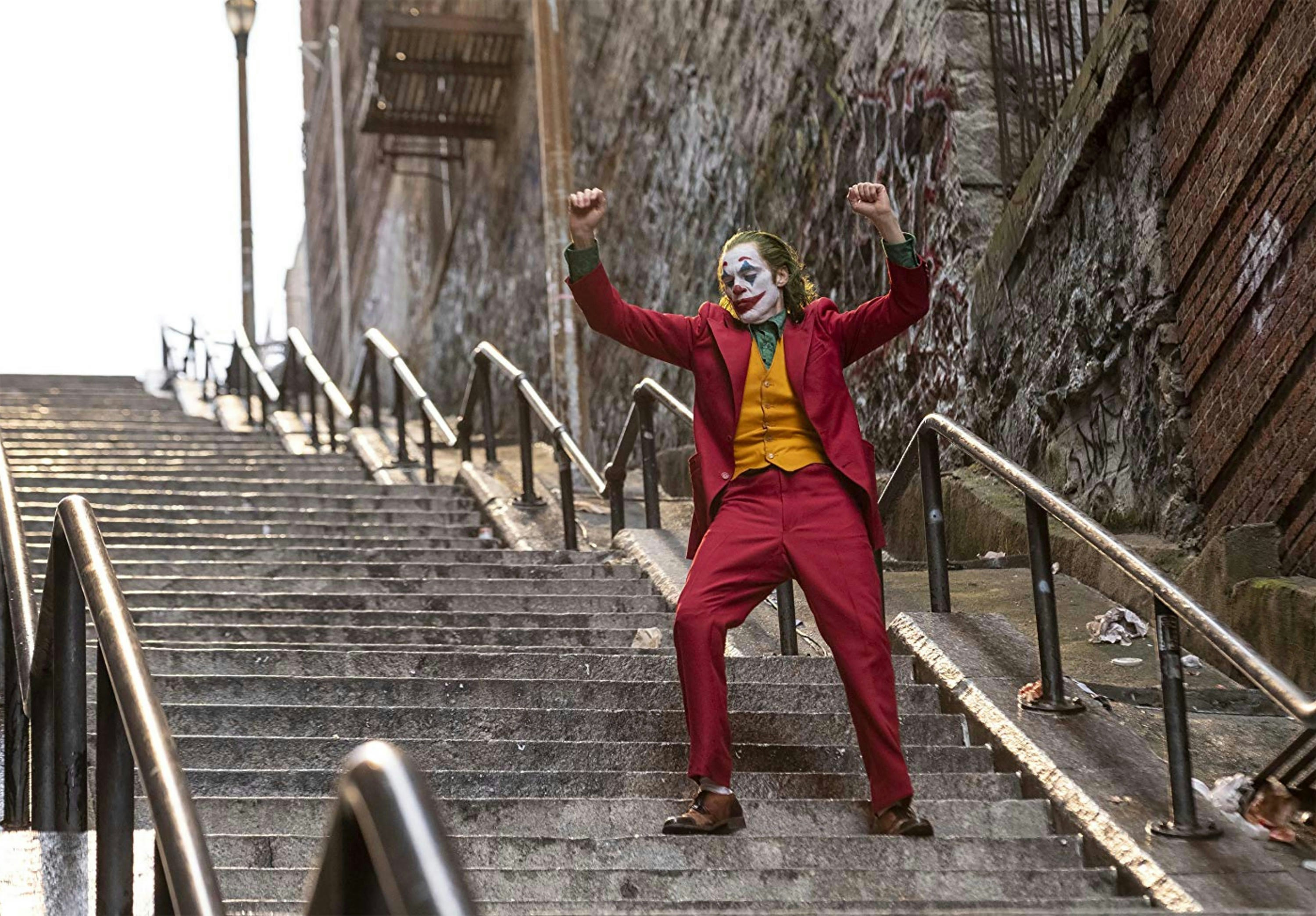 A still from the movie 'Joker': the Joker is dancing down a flight of concrete steps in New York.