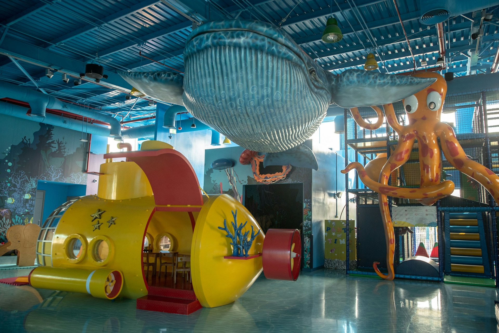 A mock submarine has been fashioned in the kids area at Jumerirah Beach Hotel, Dubai. Overhead, a model blue whale is visible.