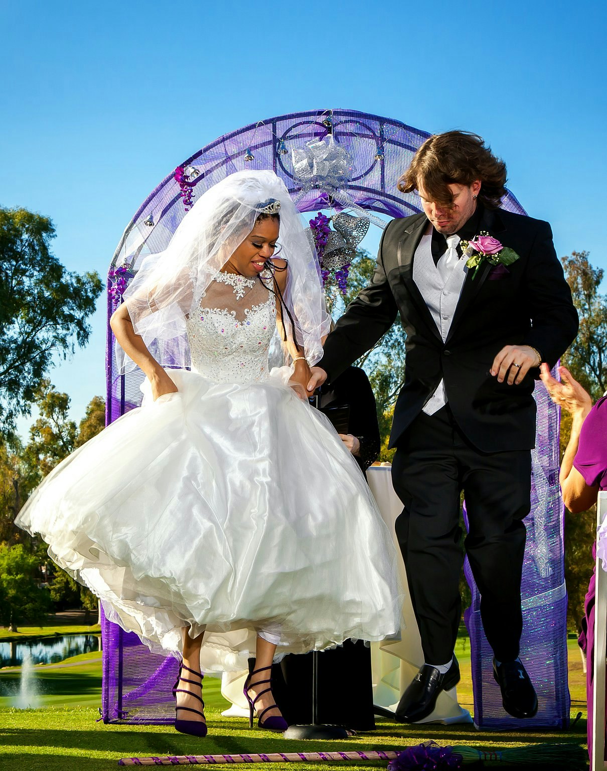 A bride and groom jump over a broom at their wedding ceremony in the USA.