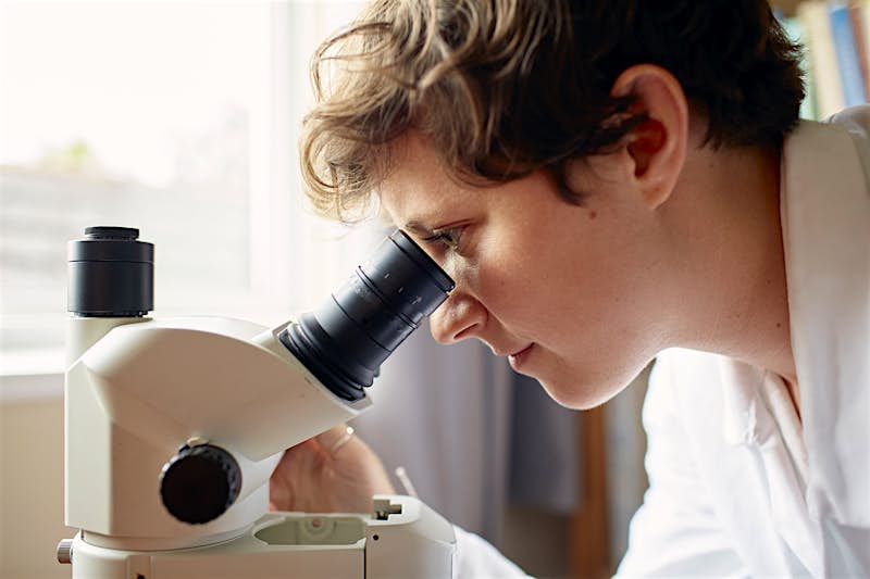 Scientist Kirstie Jones-Williams looks through a lab microscope