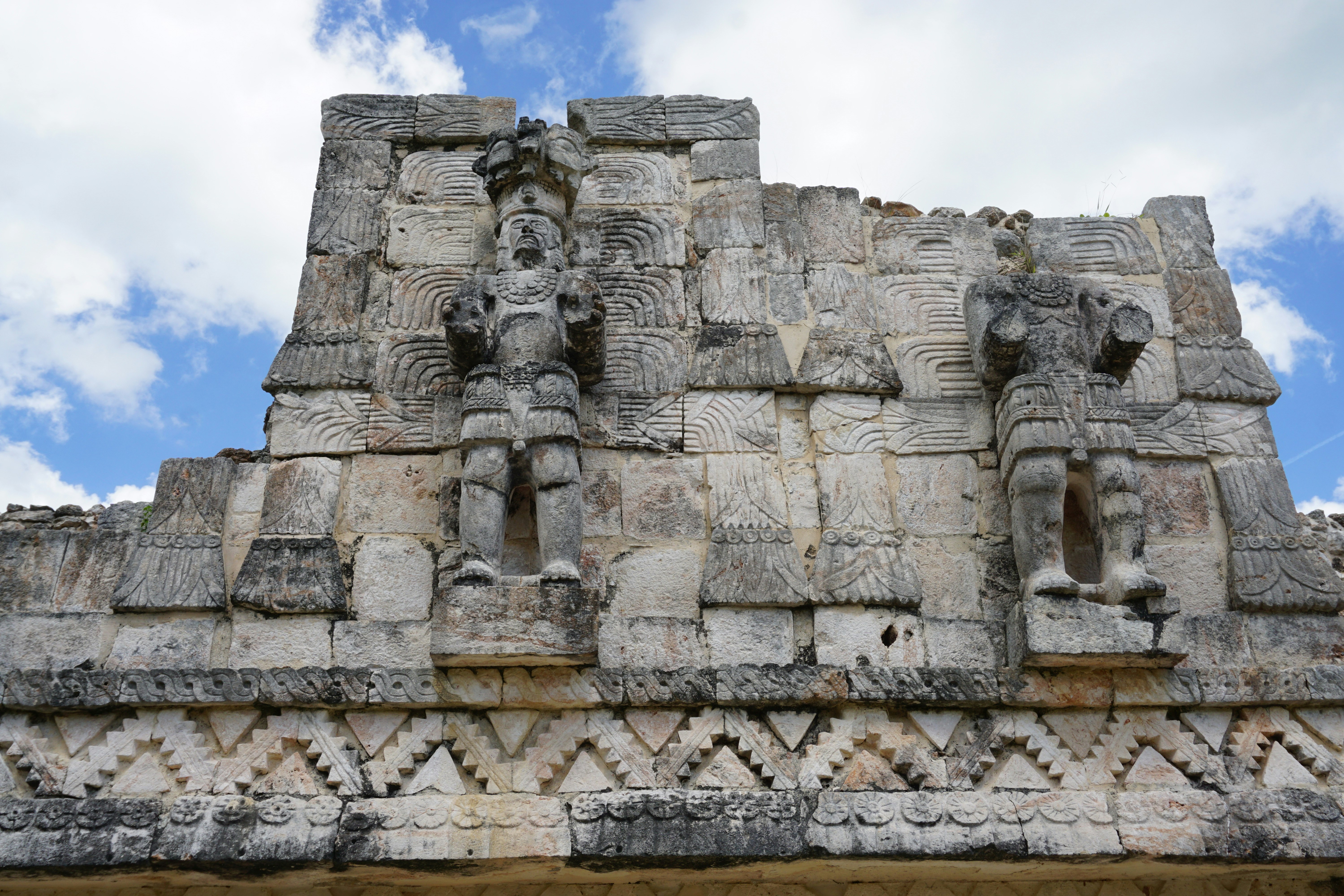 Stone reliefs of Mayan gods on the side of a pyramid