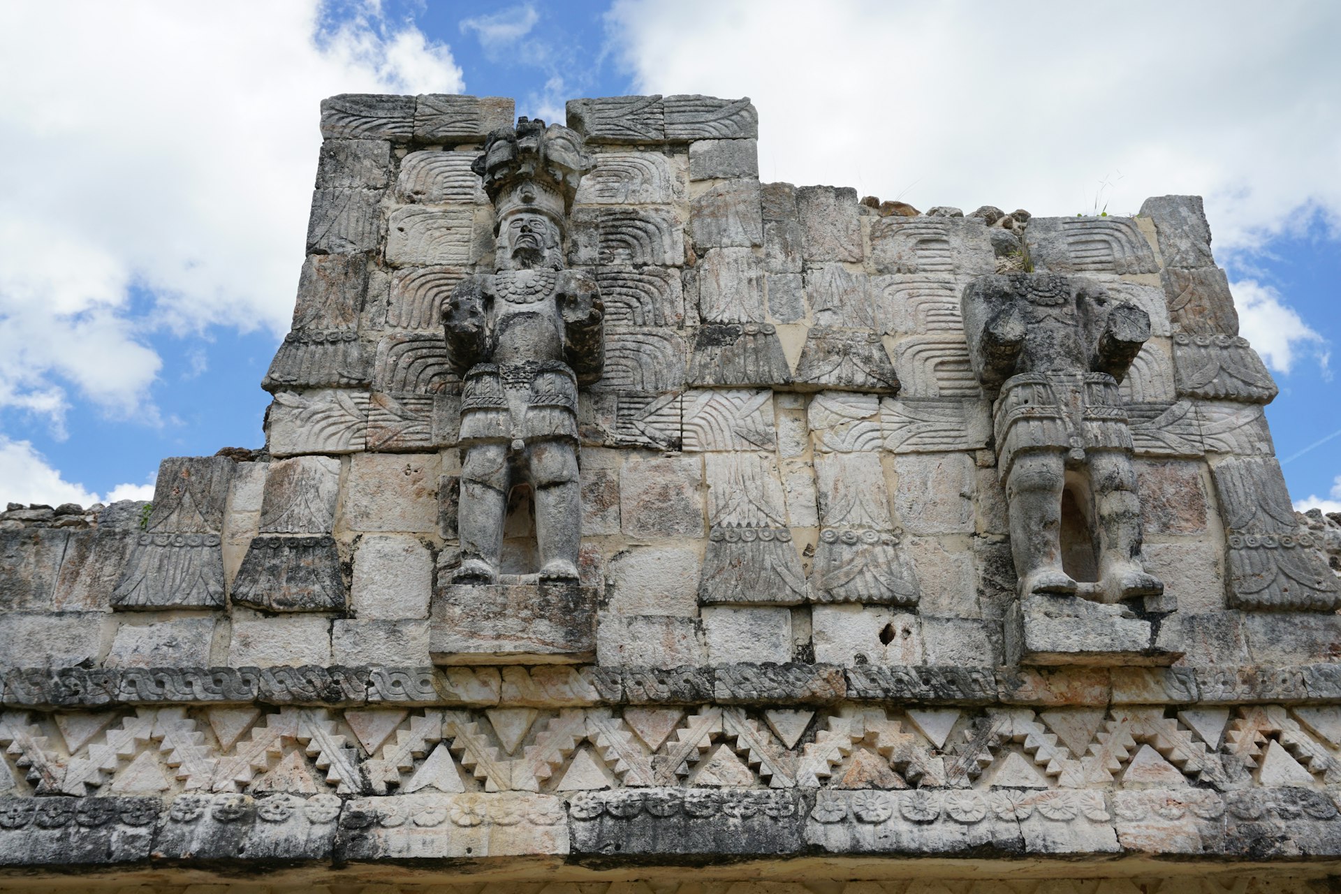 Stone reliefs of Mayan gods on the side of a pyramid