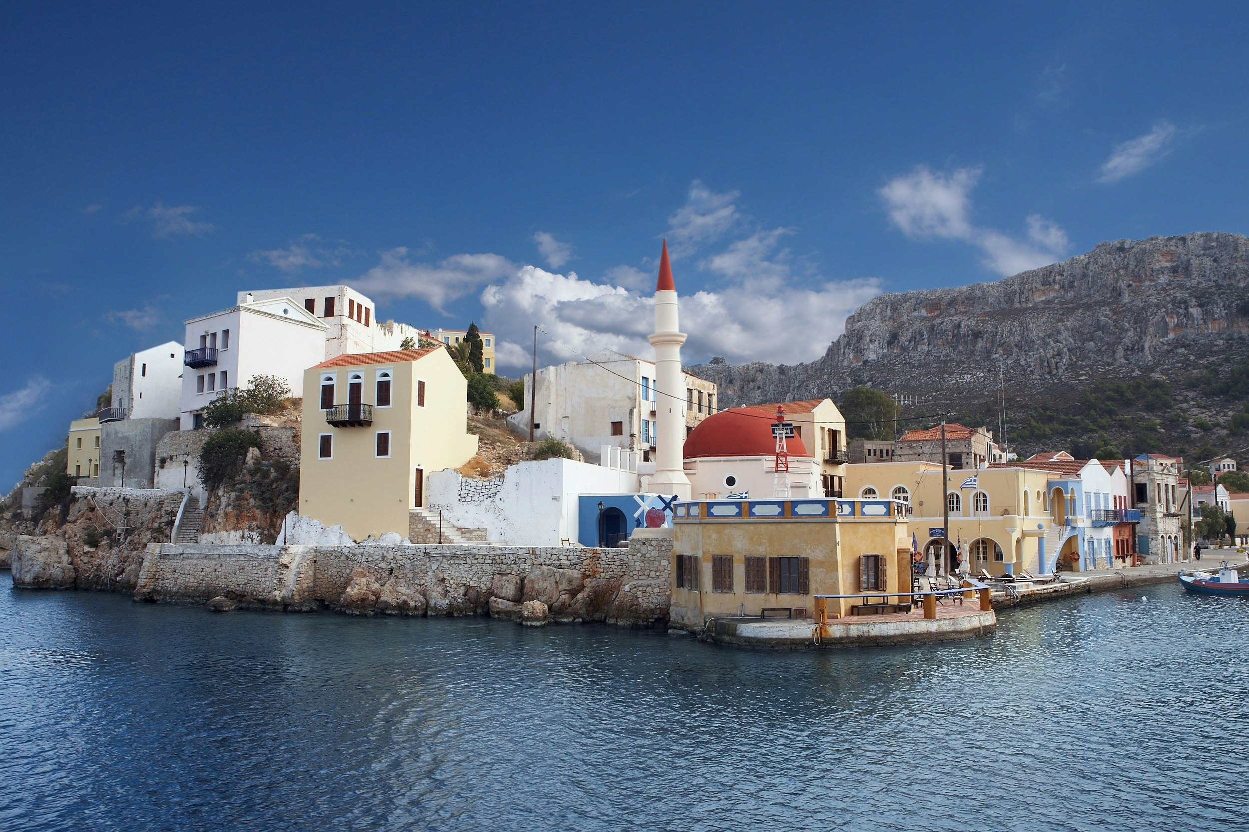 A rocky island lined with pastel-coloured low-rise buildings.