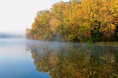 Trees with fall foliage border a lake with fog at Bedford-Katonah in upstate New York