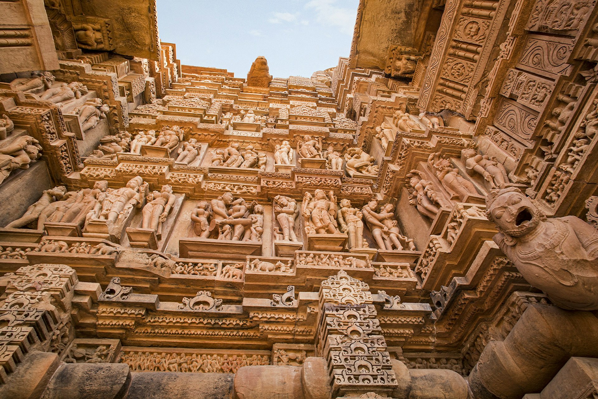 An image from the ground looking up at walls covered in sandstone sculptures and carvings. Madhya Pradesh, India.