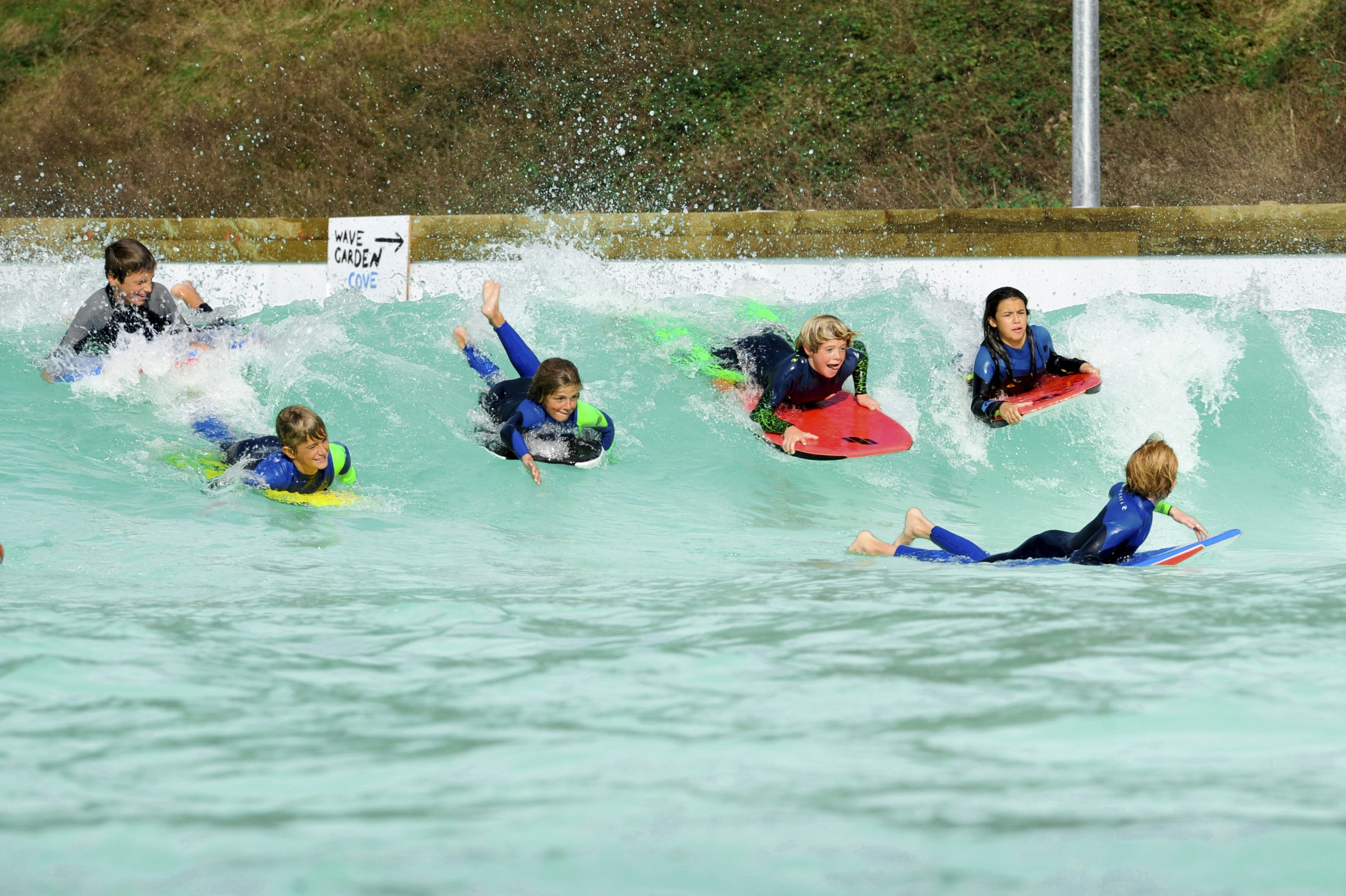 Young surfers riding waves at an inland surf park on a sunny day