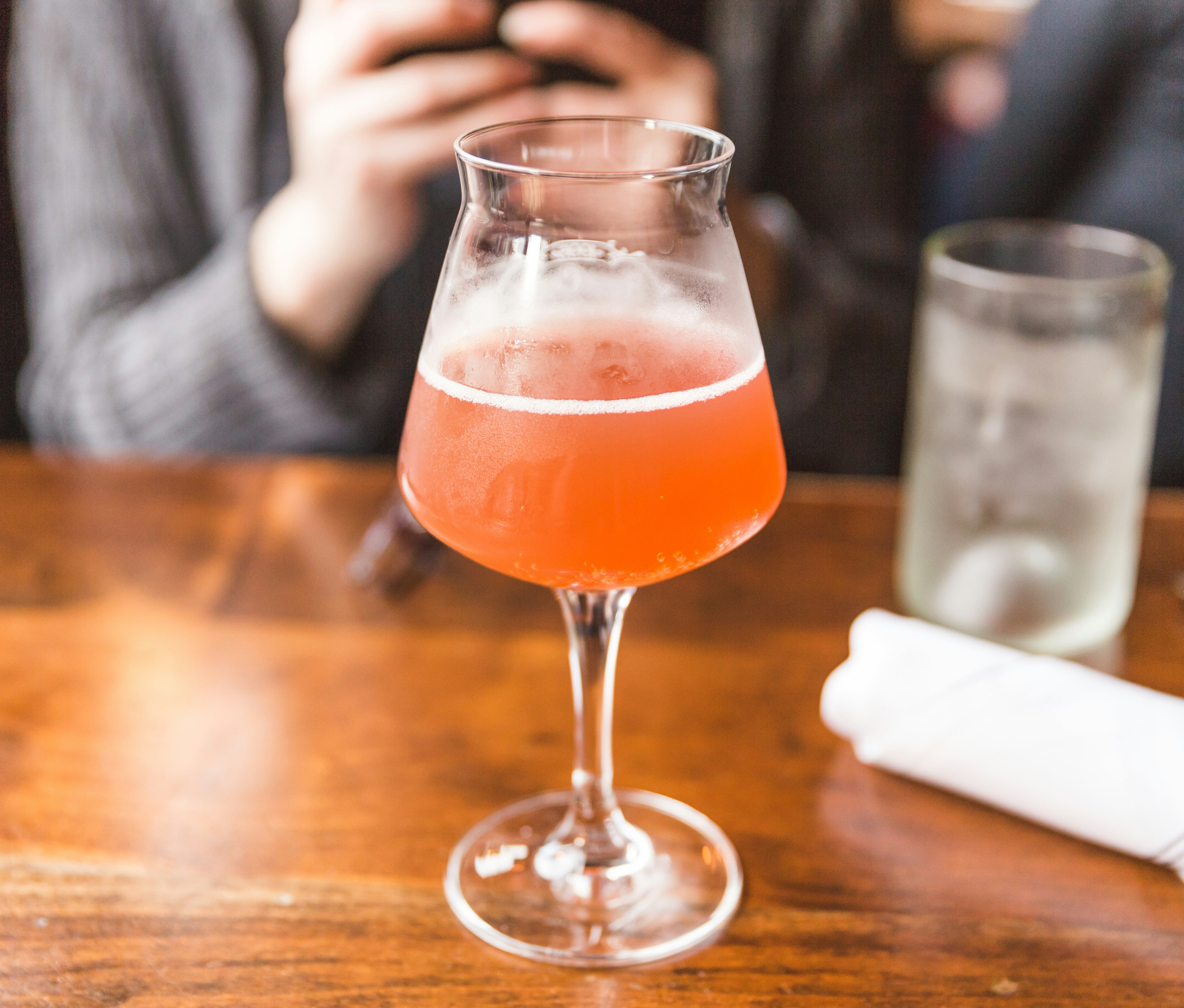 A tall glass filled with kombucha sits on a wooden surface; vegan restaurant Miami