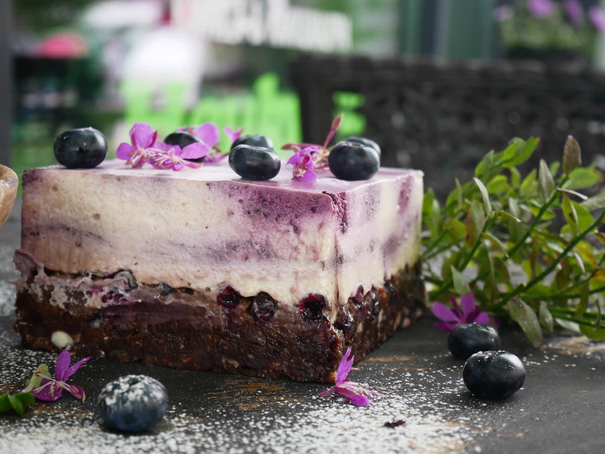 A close-up of a slice of blueberry cheesecake with some whole blueberries on top.