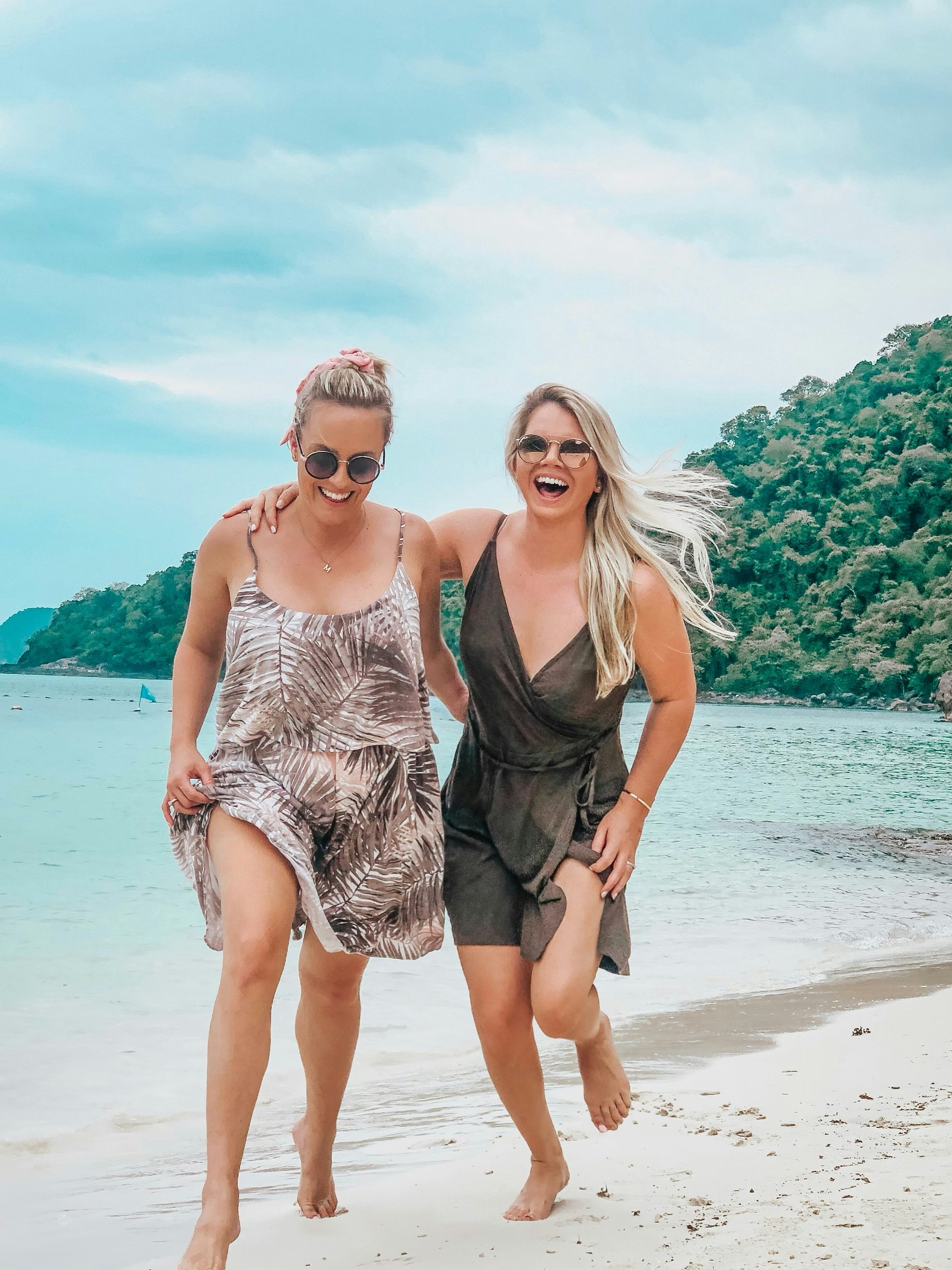 Whitney and Megan smiling and laughing on the beach of a tropical island in Thailand's Ang Thong Marine National Park.