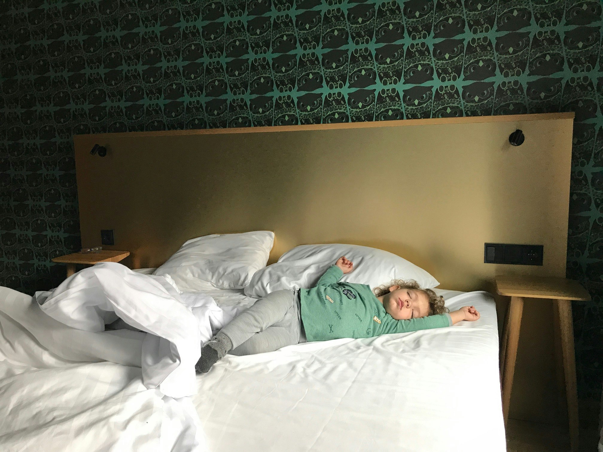 A child sleeps sprawled out in a hotel bed.