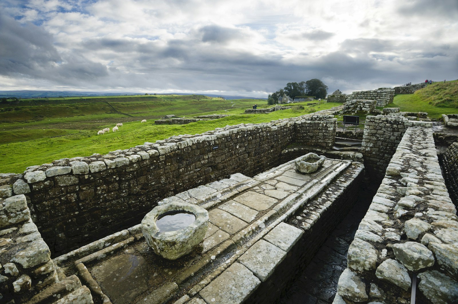 Latrines at Hadrian's Wall with cloudy skies and green moors in the background