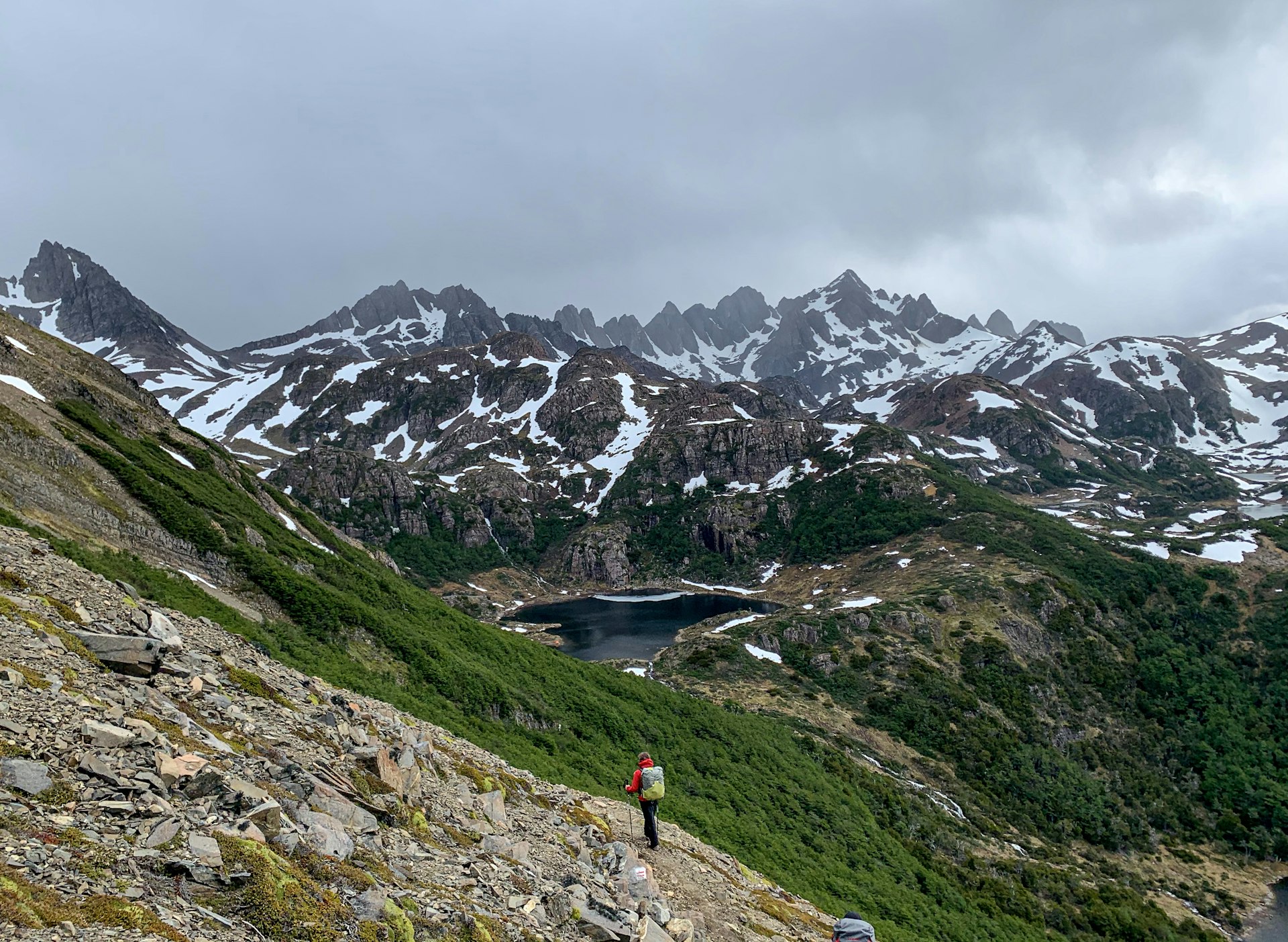 A hiker looks small amidst the vast expanse of jagged mountains of the Dientes de Navarino.