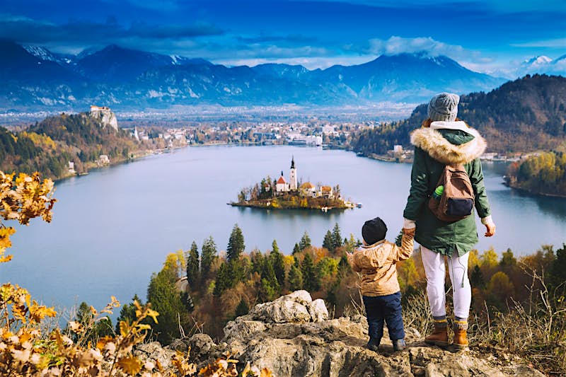 An adult and child look down over Lake Bled in Slovenia from a hilltop