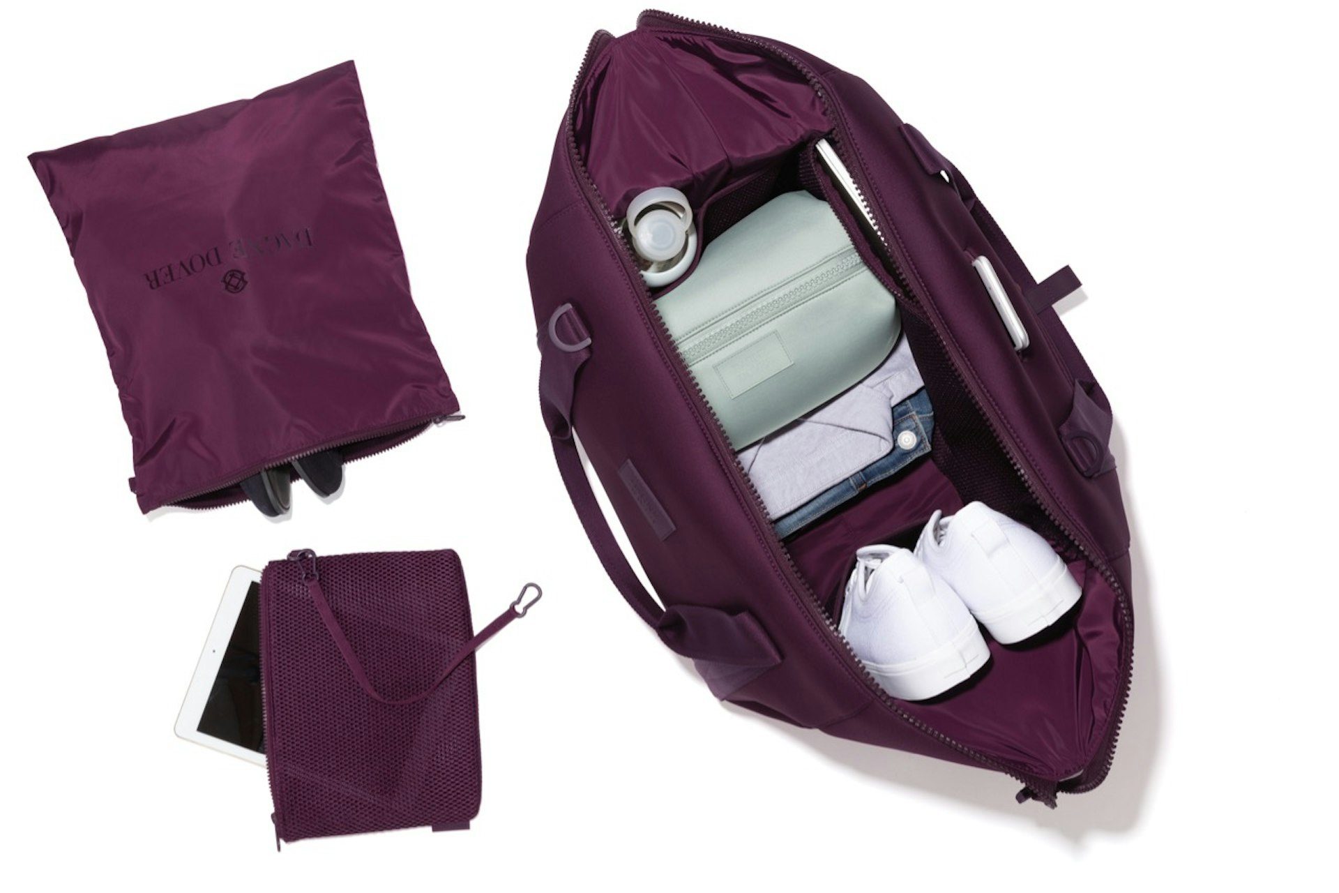 Dagne Dover's extra-large Landon Carryall in eclipse (purple), open to show shoes, water bottle, clothes, etc. next to a shoe bag and a pouch with key leash