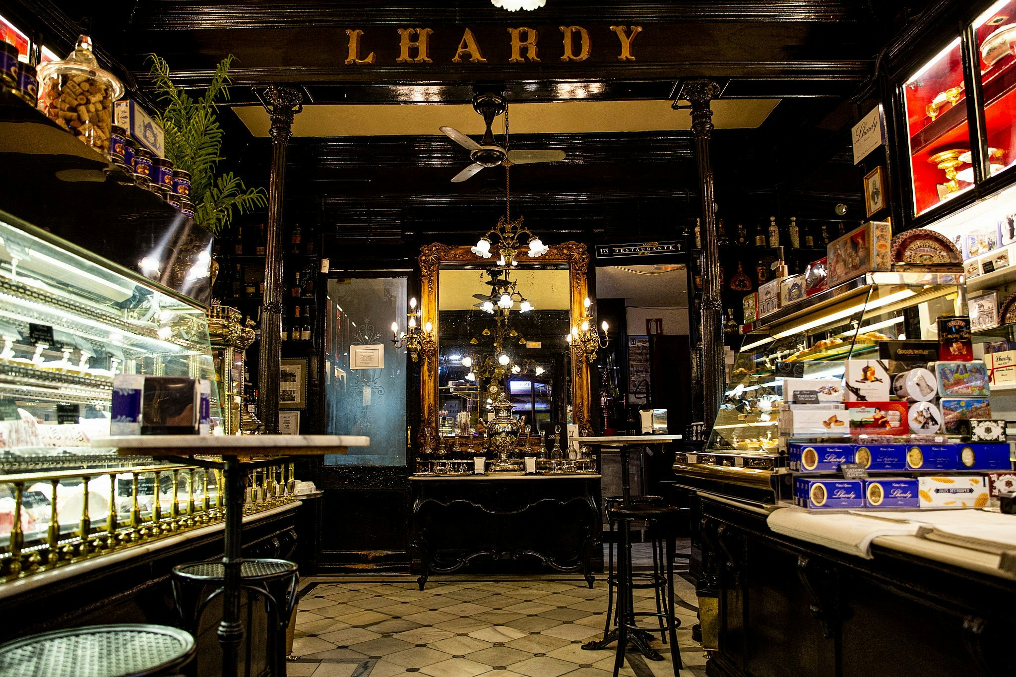 The opulent interior of Lhardy, with gilded fixtures, dark wood panelling and a white tiled floor.