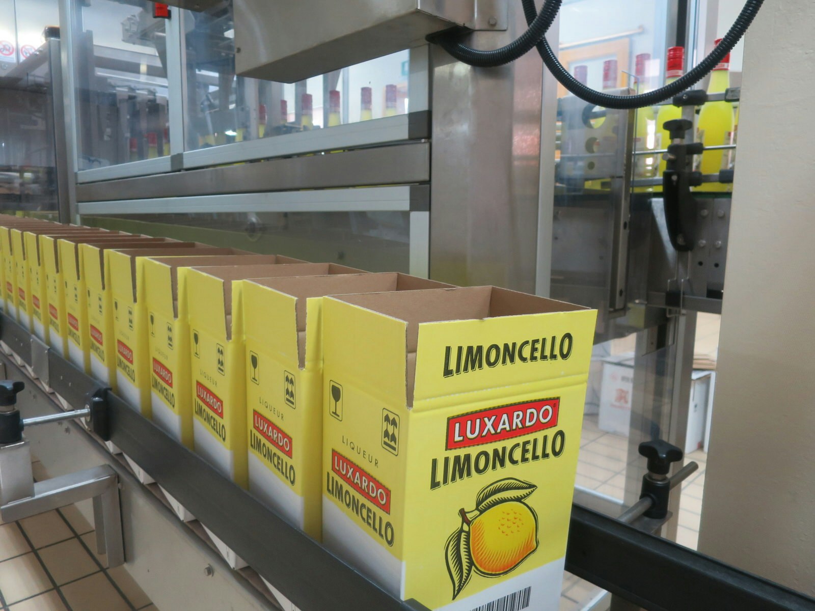 flera gula kartonger med märket Luxardo Limoncello är uppradade på ett löpande band, redo att förseglas