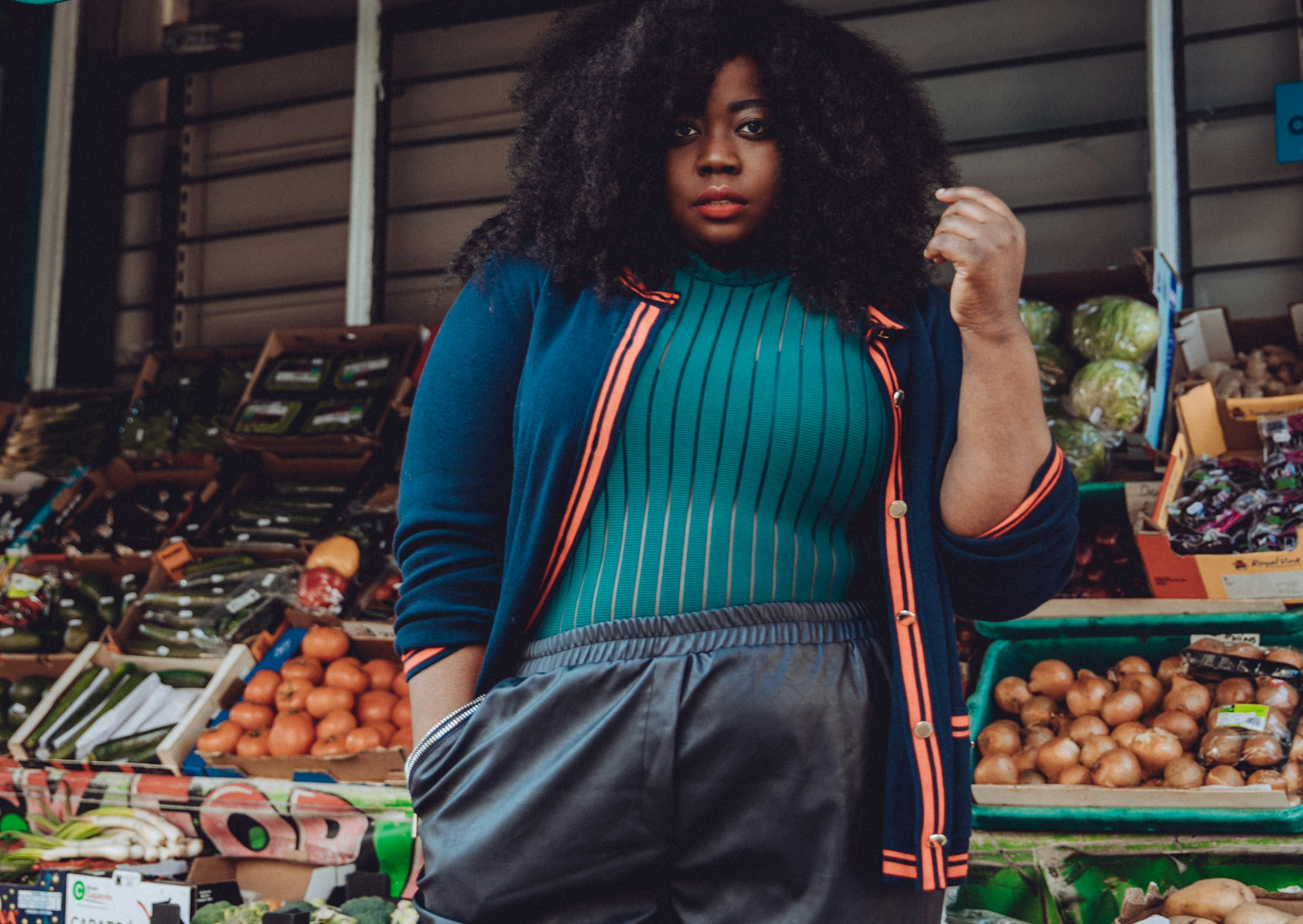 Stephanie Yeboah poses in front of a market stall in a green top and blue cardigan.