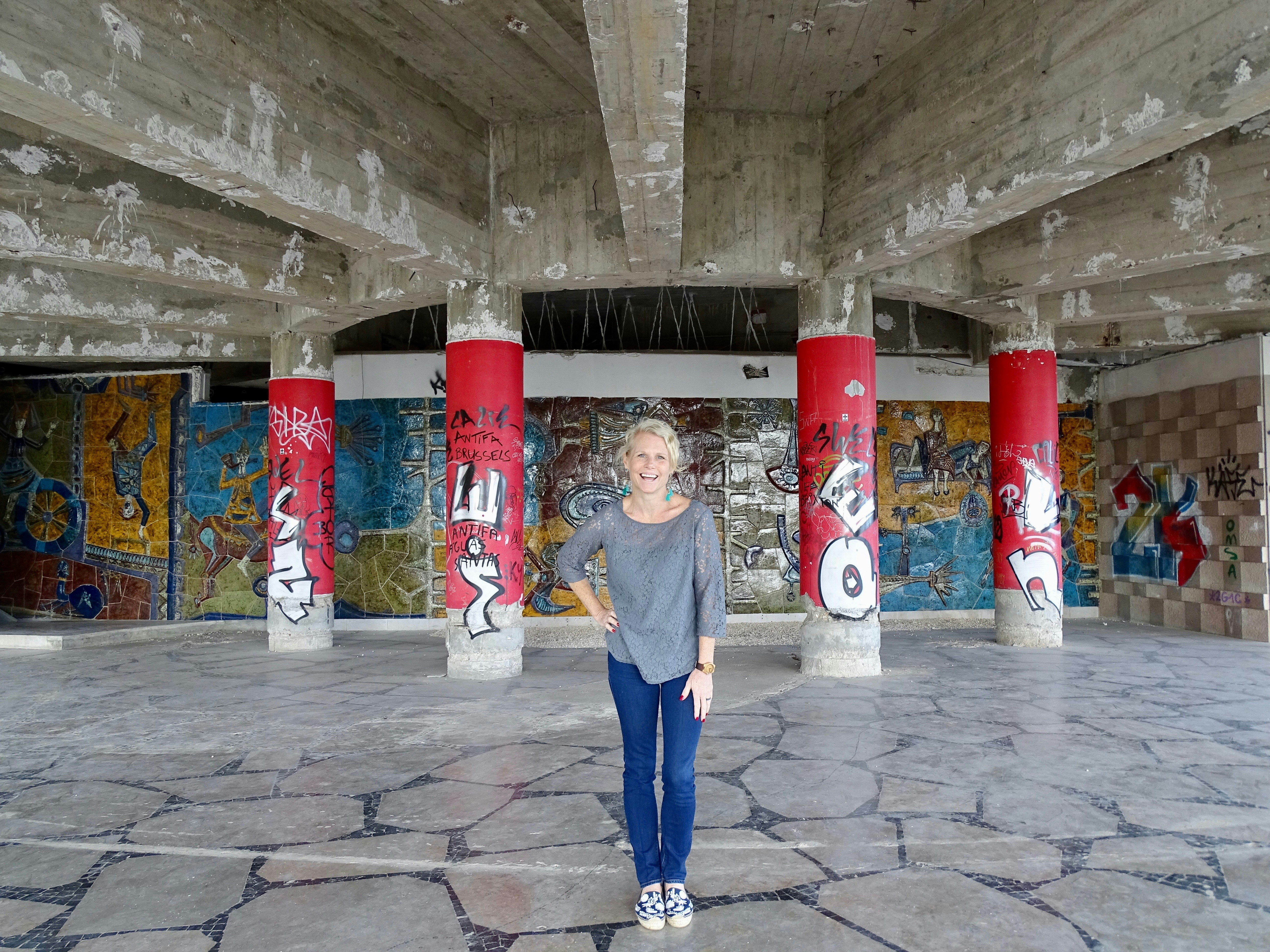 A woman poses smiling in front of graffitied columns in the Miradouro Panoramico de Monsanto, Lisbon. 