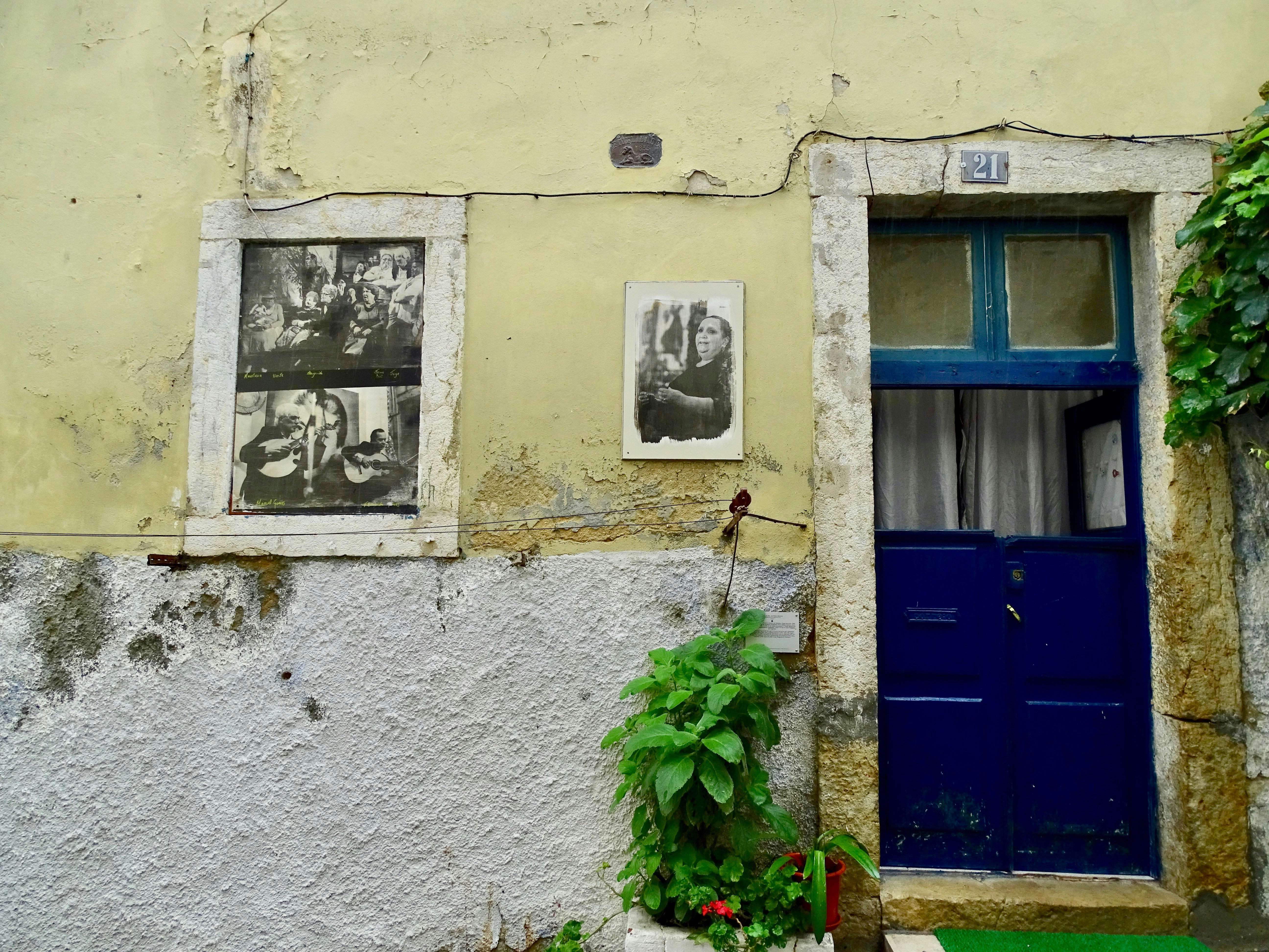 Black and white photographic street art in place of a window on the side of a house in Lisbon.