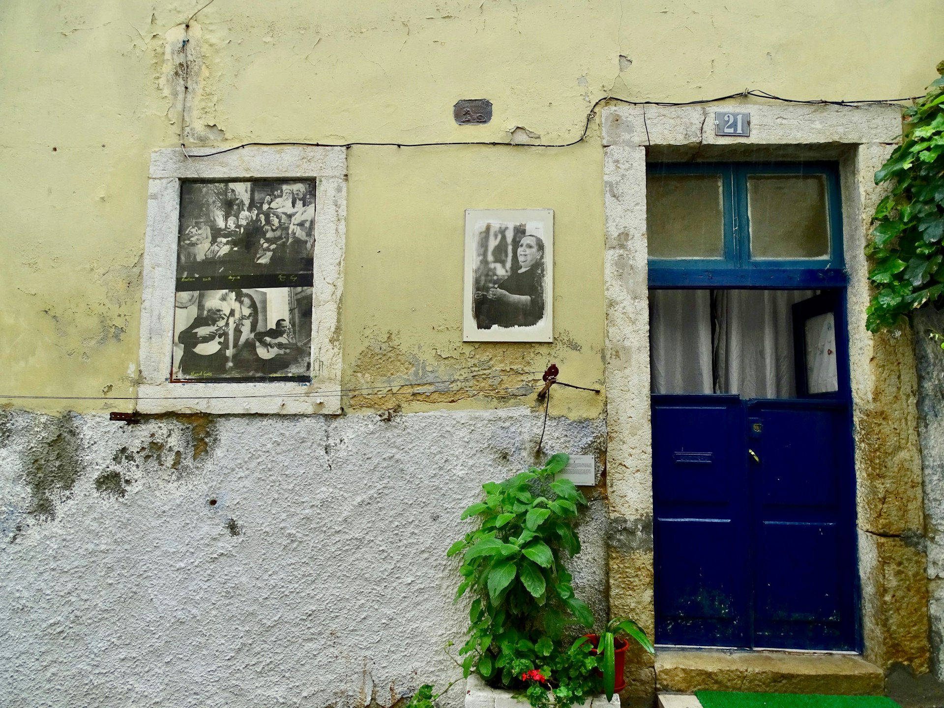 Black and white photographic street art in place of a window on the side of a house in Lisbon.