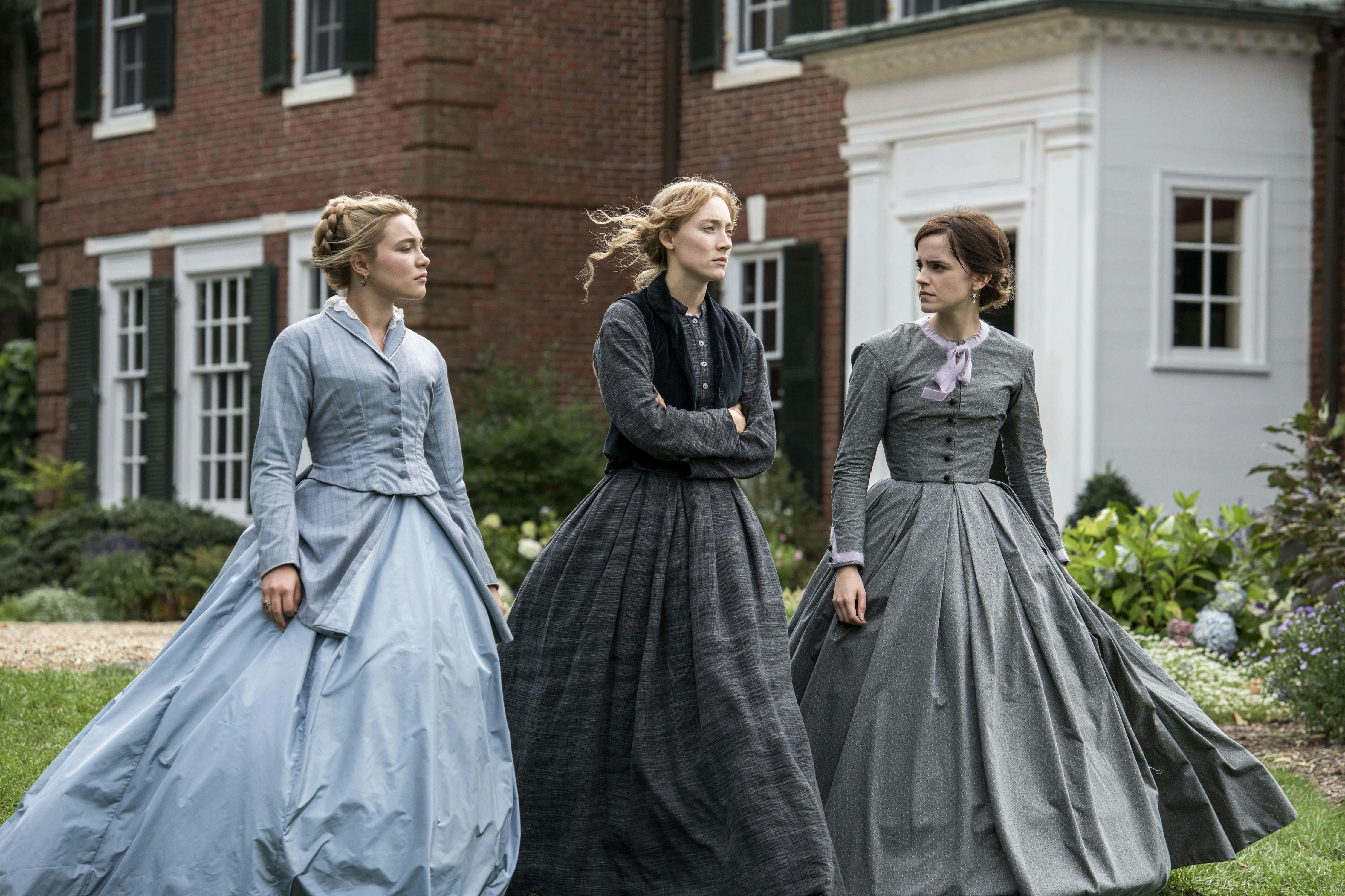 Florence Pugh, Saoirse Ronan and Emma Watson striding in period costume in a still from 'Little Women' (2019).