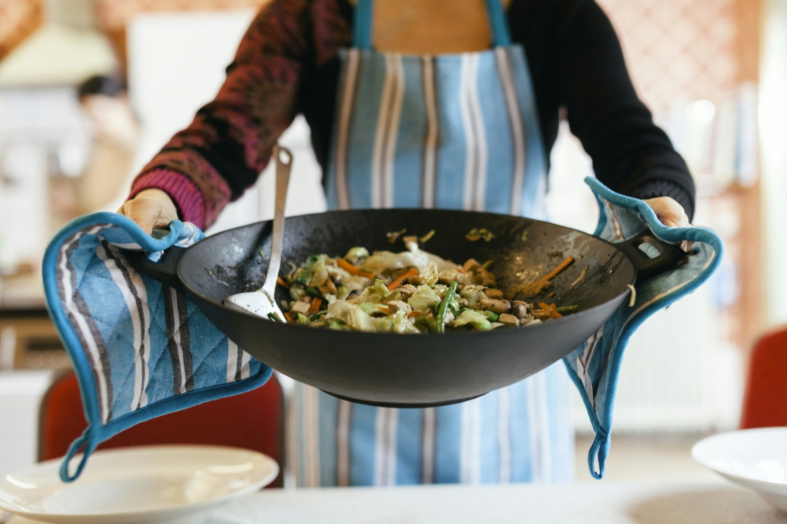 A woman serves food in a large wok
