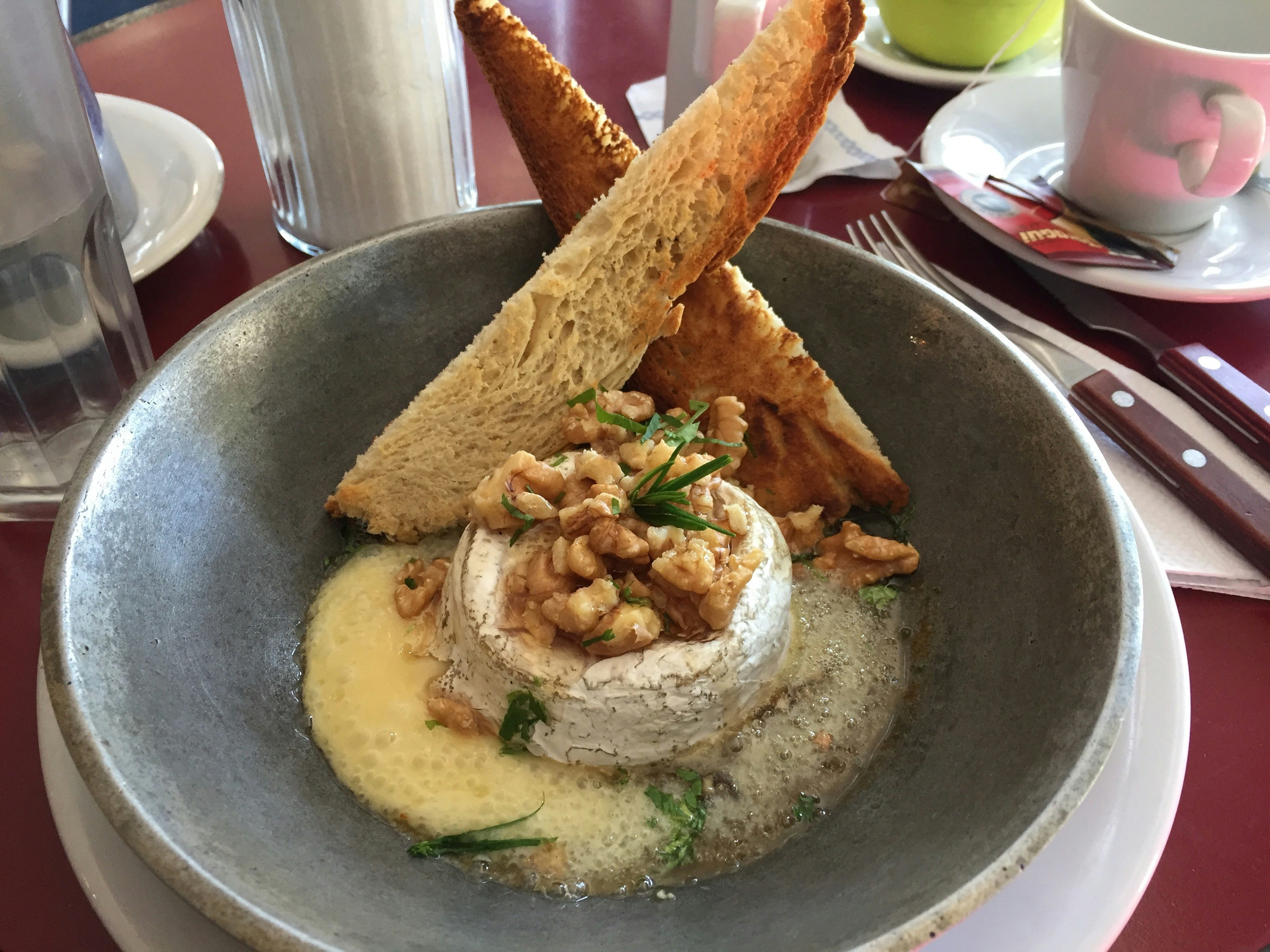 A dish at Lo del Francés; a gray bowl contains a small baked camembert cheese, walnuts and two artistically arranged slices of toast.