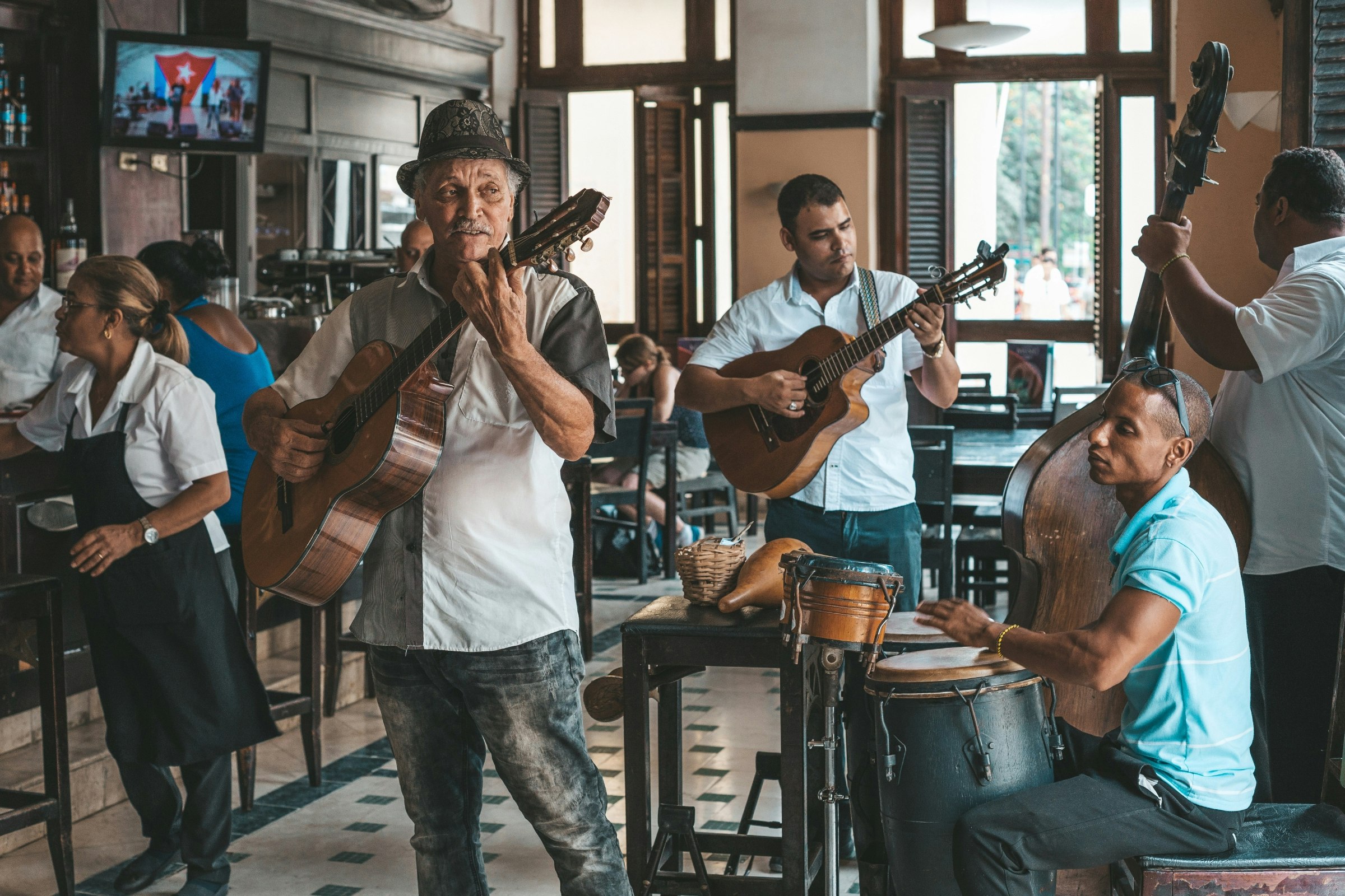 A local four-piece band play in a restaurant in Havana, Cuba. Two of the musicians play guitar, one plays bass and one plays drums. 