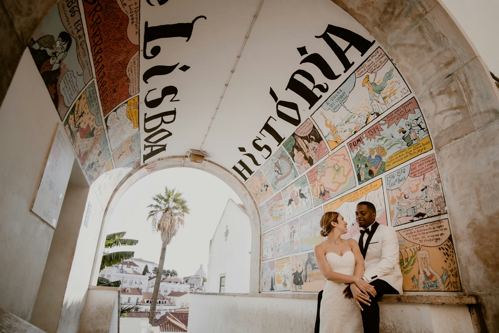 A couple sit in a frescoed corridor on their wedding day.