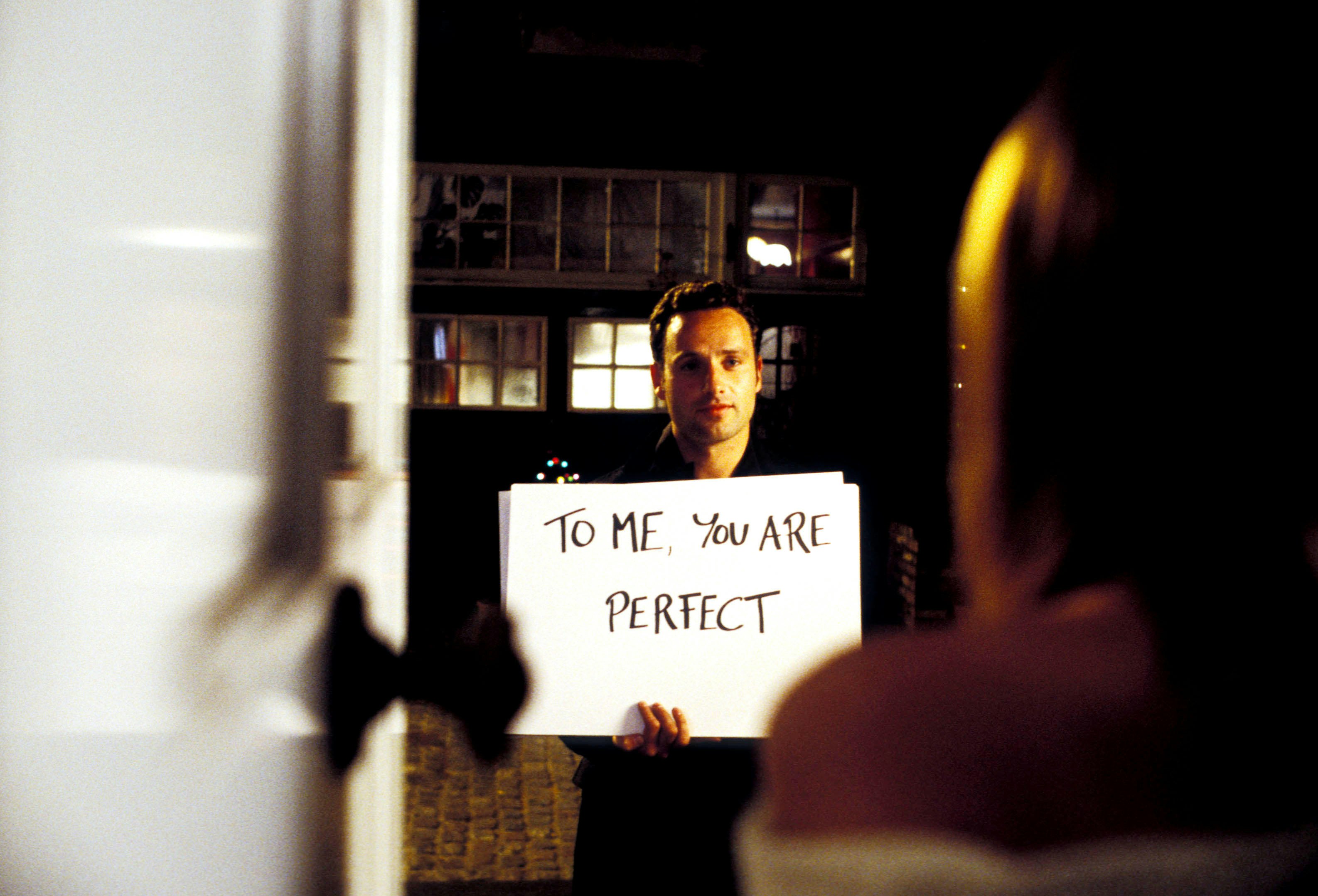 Actor Andrew Lincoln holds a sign that says 'to me you are perfect' in an iconic scene from Love Actually