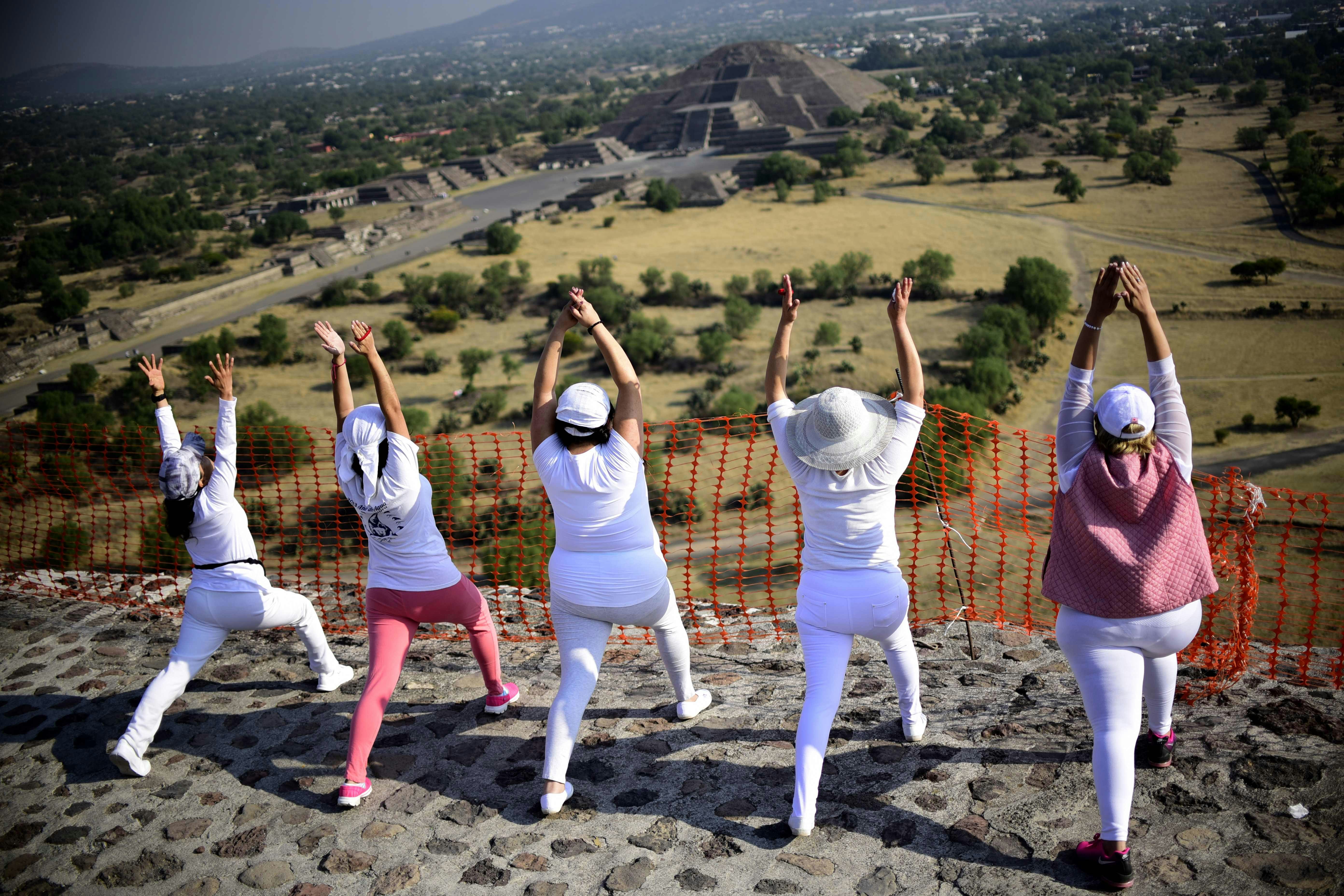 Women atop the Pyramid of the Sun at the archaeological site of Teotihuacan, in the municipality of Teotihuacan, northeast of Mexico City, stretch and "get energy" from the sun as it rises during celebrations of the spring equinox