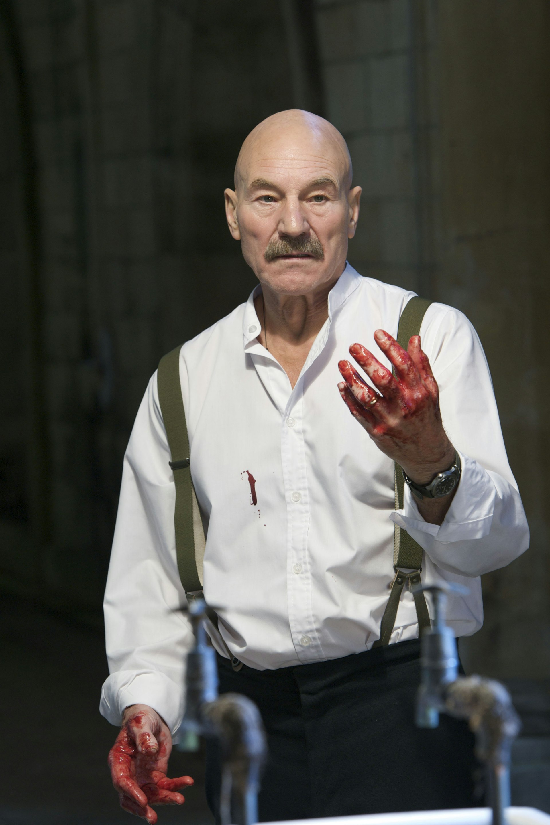 A bald man with a moustache and bloody hands