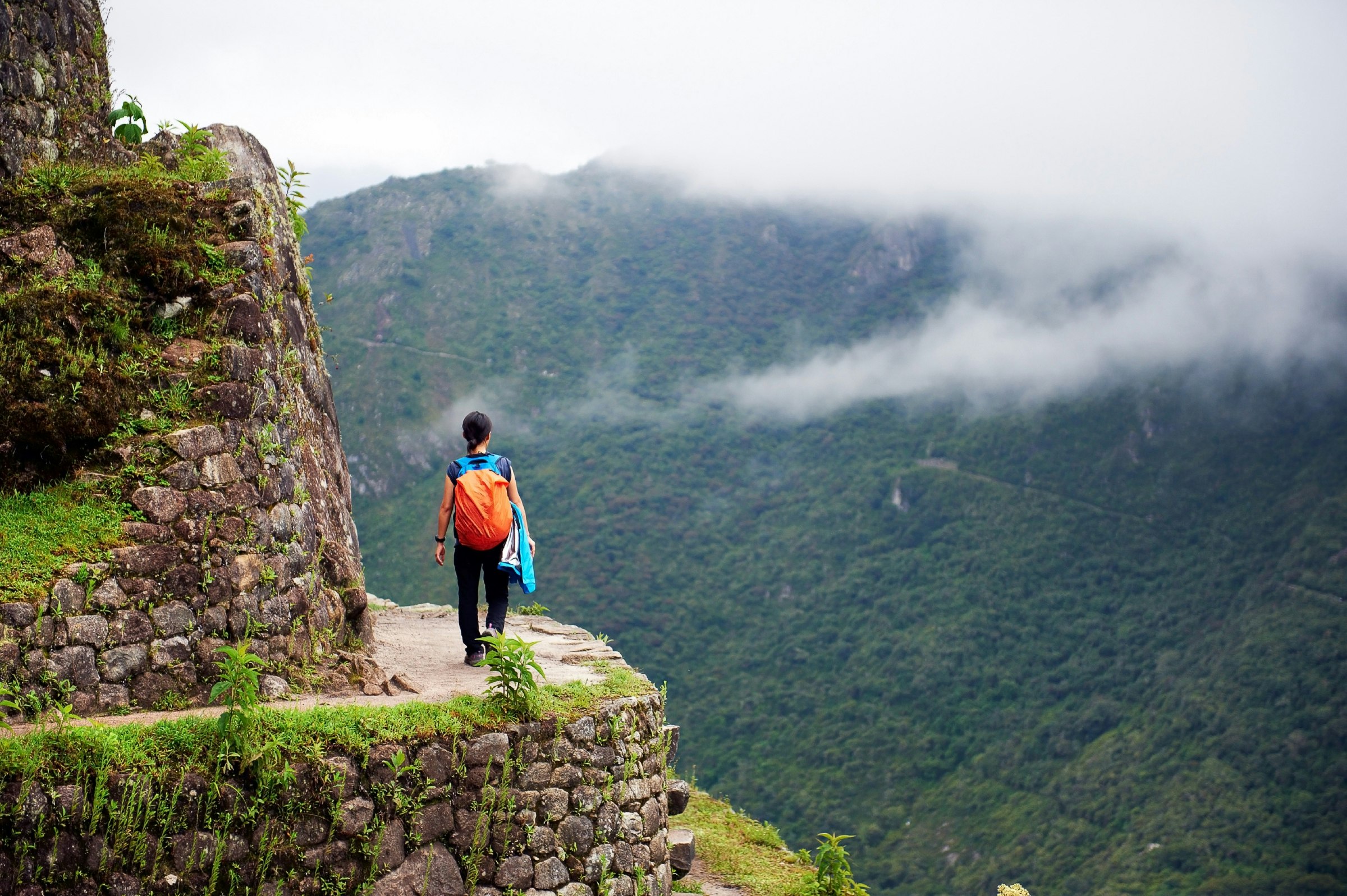 Woman walking on the edge of a cliff at Machu Picchu. 