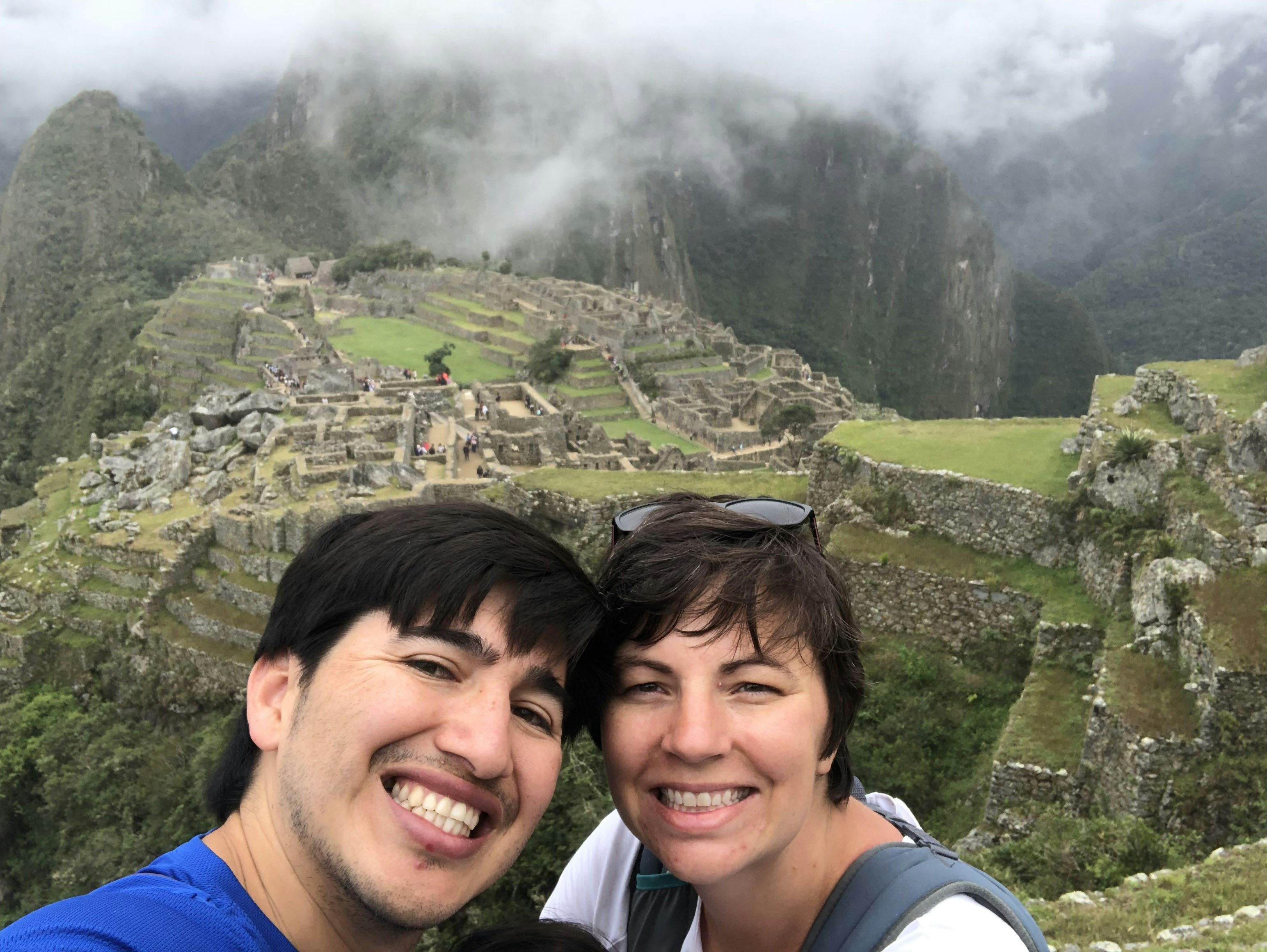 A man and a woman pose for the camera with the Inca ruins of Machu Picchu in the background.