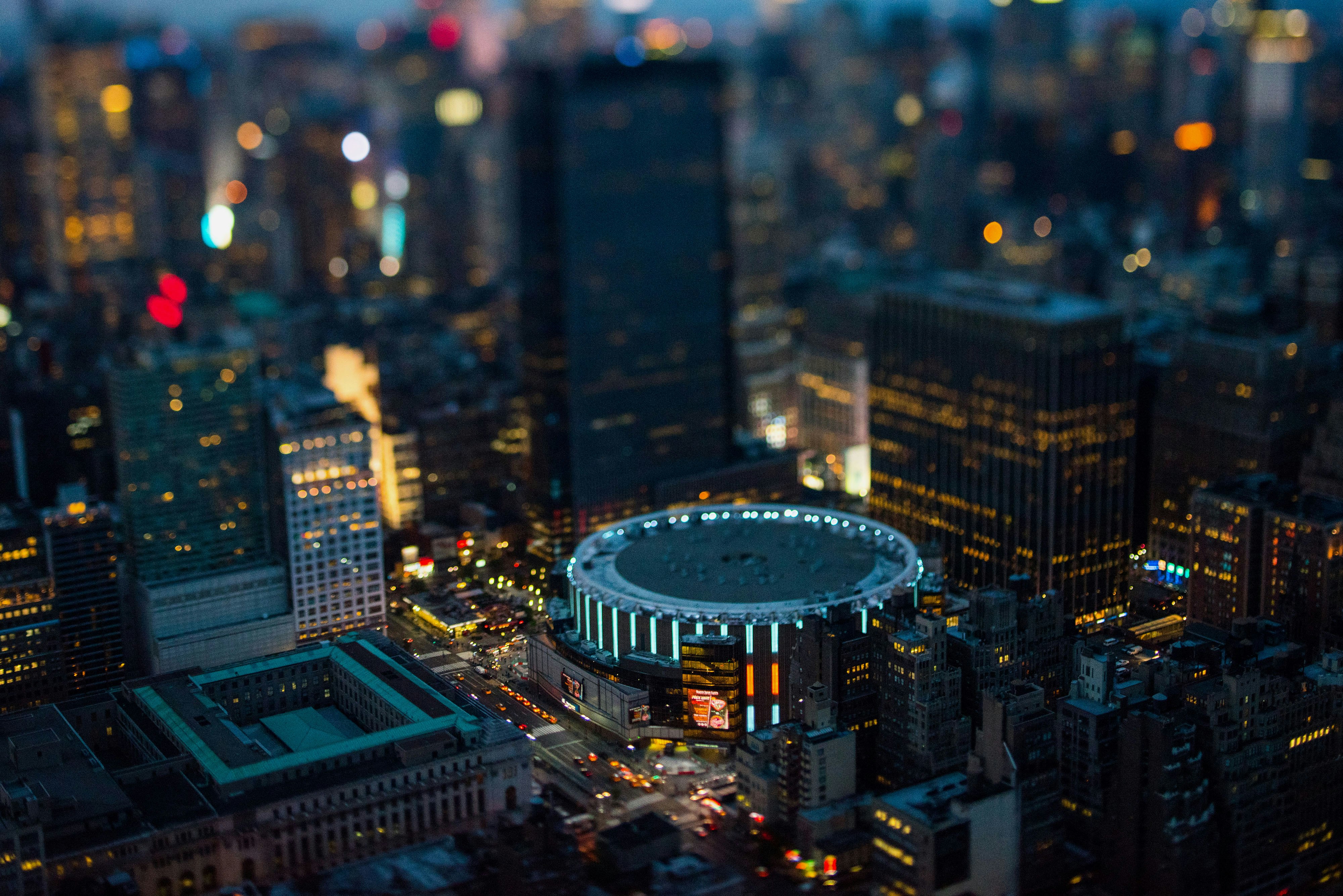 Madison Square Garden stands in Manhattan at dusk in this aerial photograph taken with a tilt-shift lens above New York