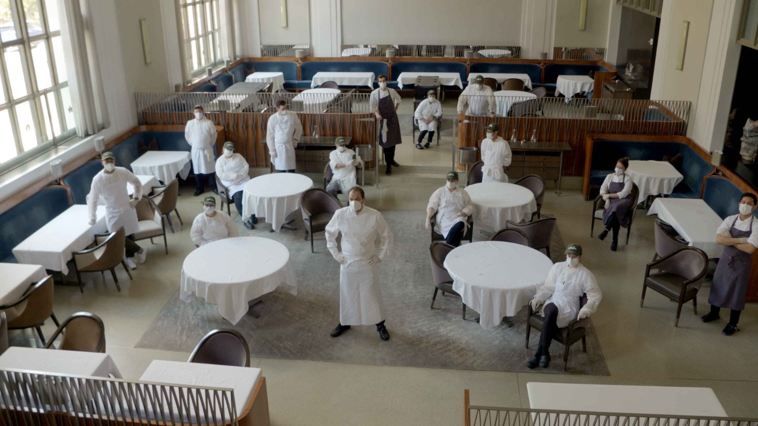 Chefs standing at tables in the dining room of a restaurant 