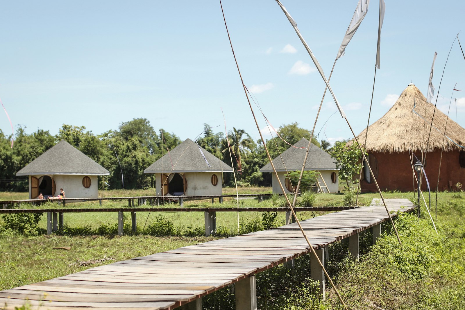 4 huts, one with a thatched roof with a boardwalk path leading to them