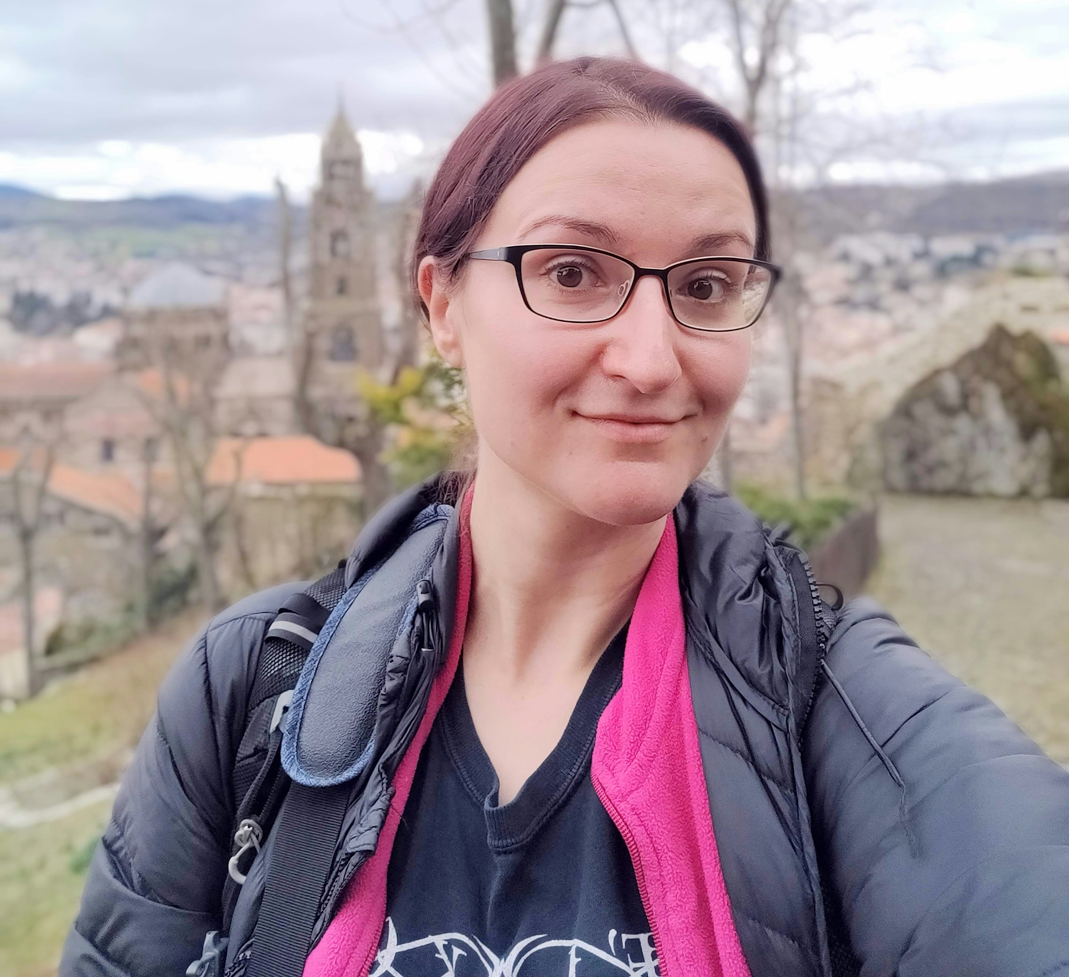 Anita Isalska poses for a selfie in front of a picturesque town in France.