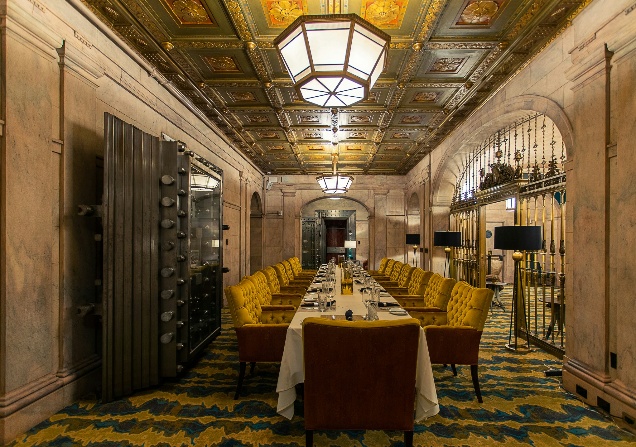 An elegant private dining space at Marble Room Steakhouse & Raw Bar; the room is a former vault, with a huge steel vault door, ornate grating and coffered ceiling.