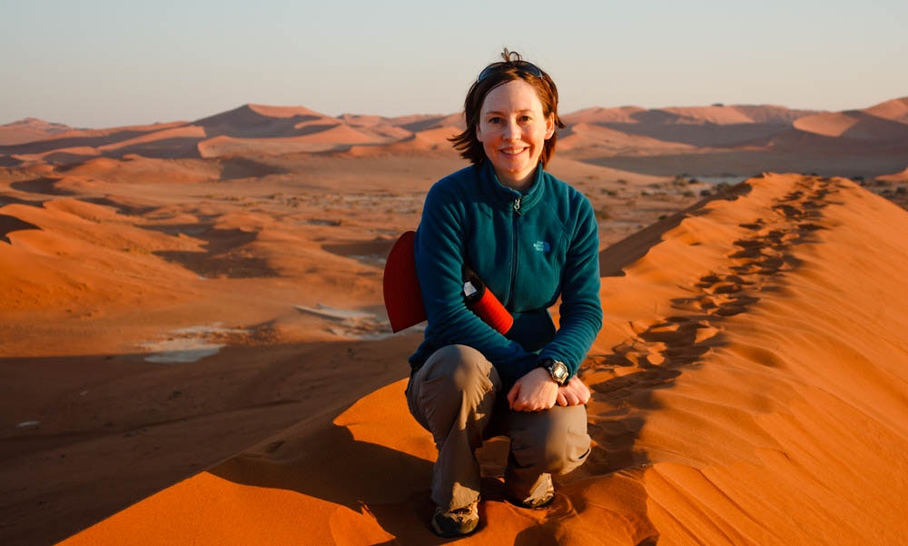 Marielena Soussvlei poses in the desert for a photograph. The sand is an orange colour. 