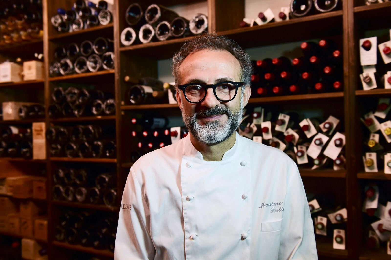 A picture of Italian chef Massimo Bottura posing in his restaurant Osteria Francescana in Modena in front of the extensive wine cellar