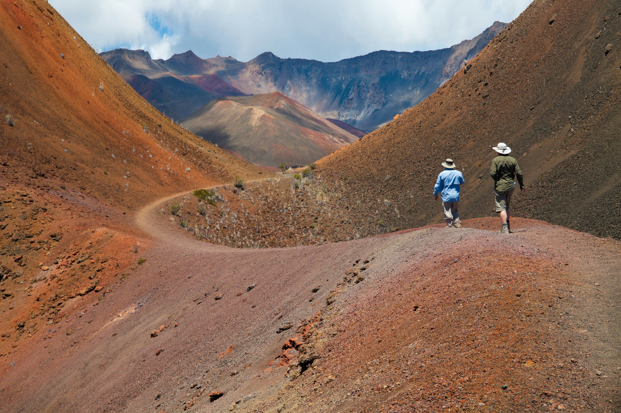 Two people hike along a trail through a volcano in Maui's Haleakala National Park; Maui sites without tourists