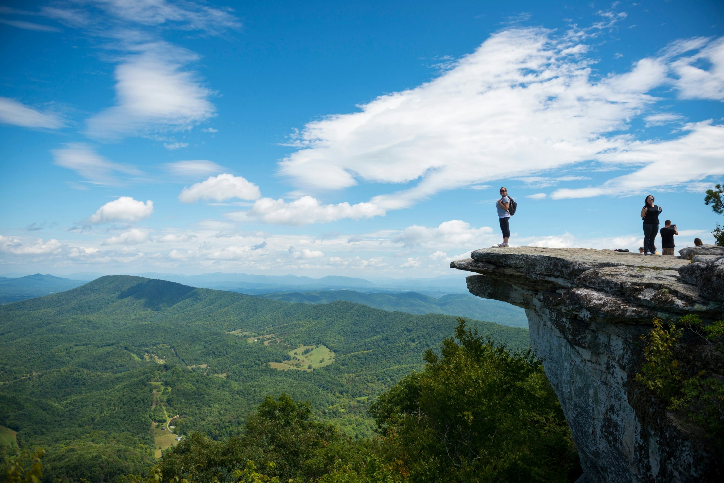 Hikers take in the view of the Appalachian Mountains from McAfee Knob on Catawba Mountain, Virginia 