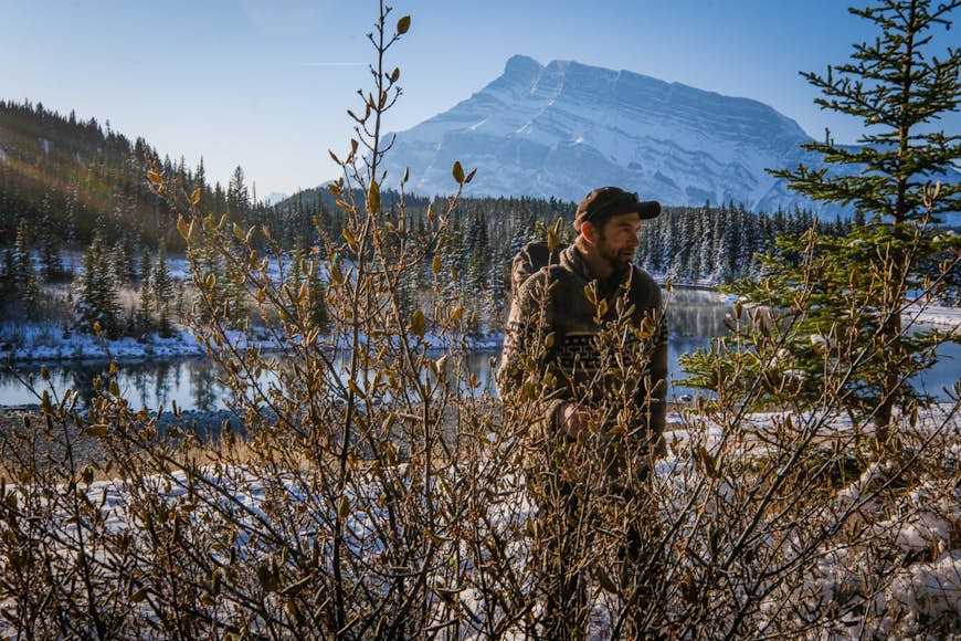 En man utforskar Cascade Park omgiven av medicinalväxter under vintern vid Banff och Lake Louise