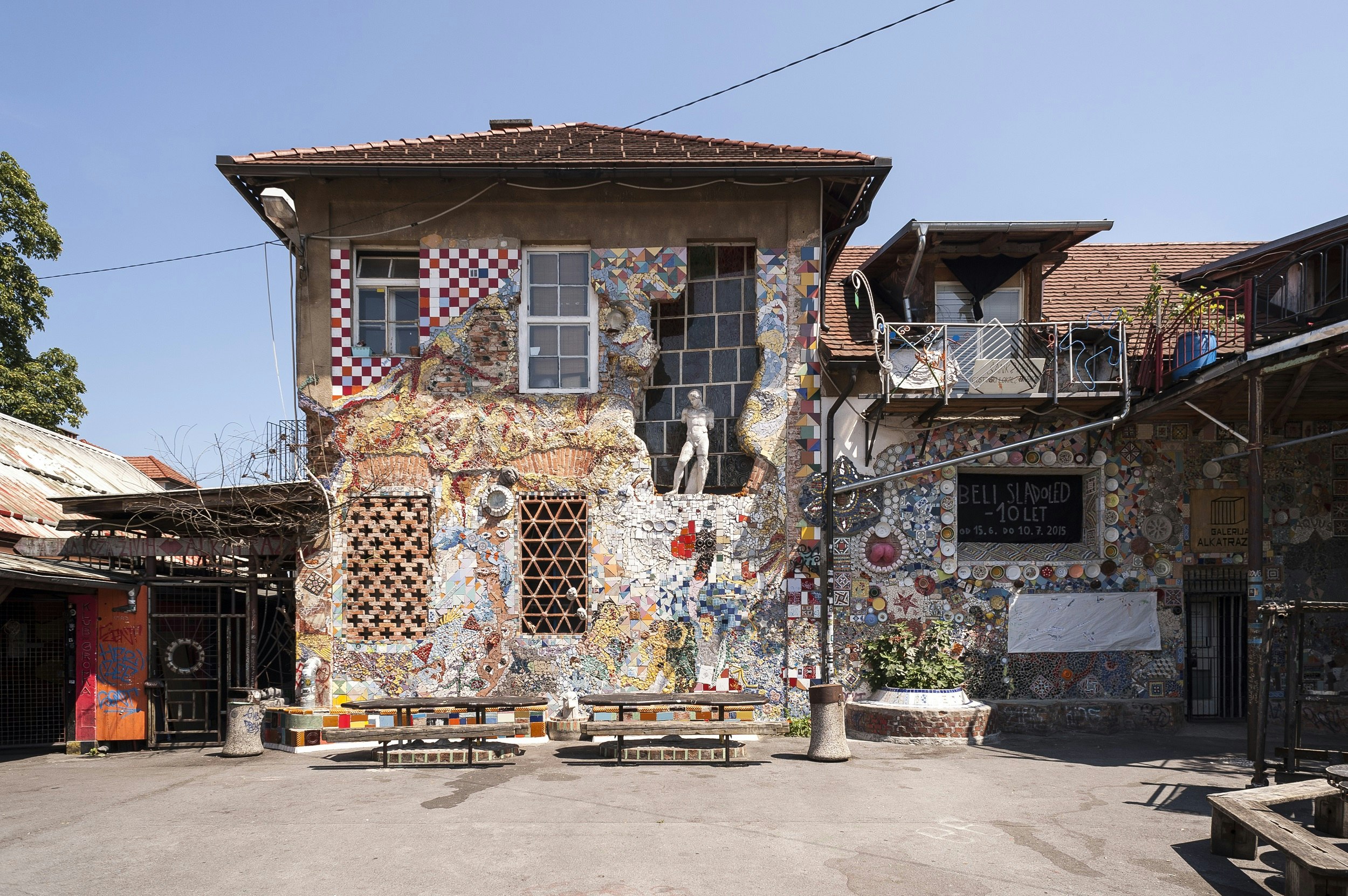 The exterior of a building covered in mosaics, sculptures, graffiti and other artworks